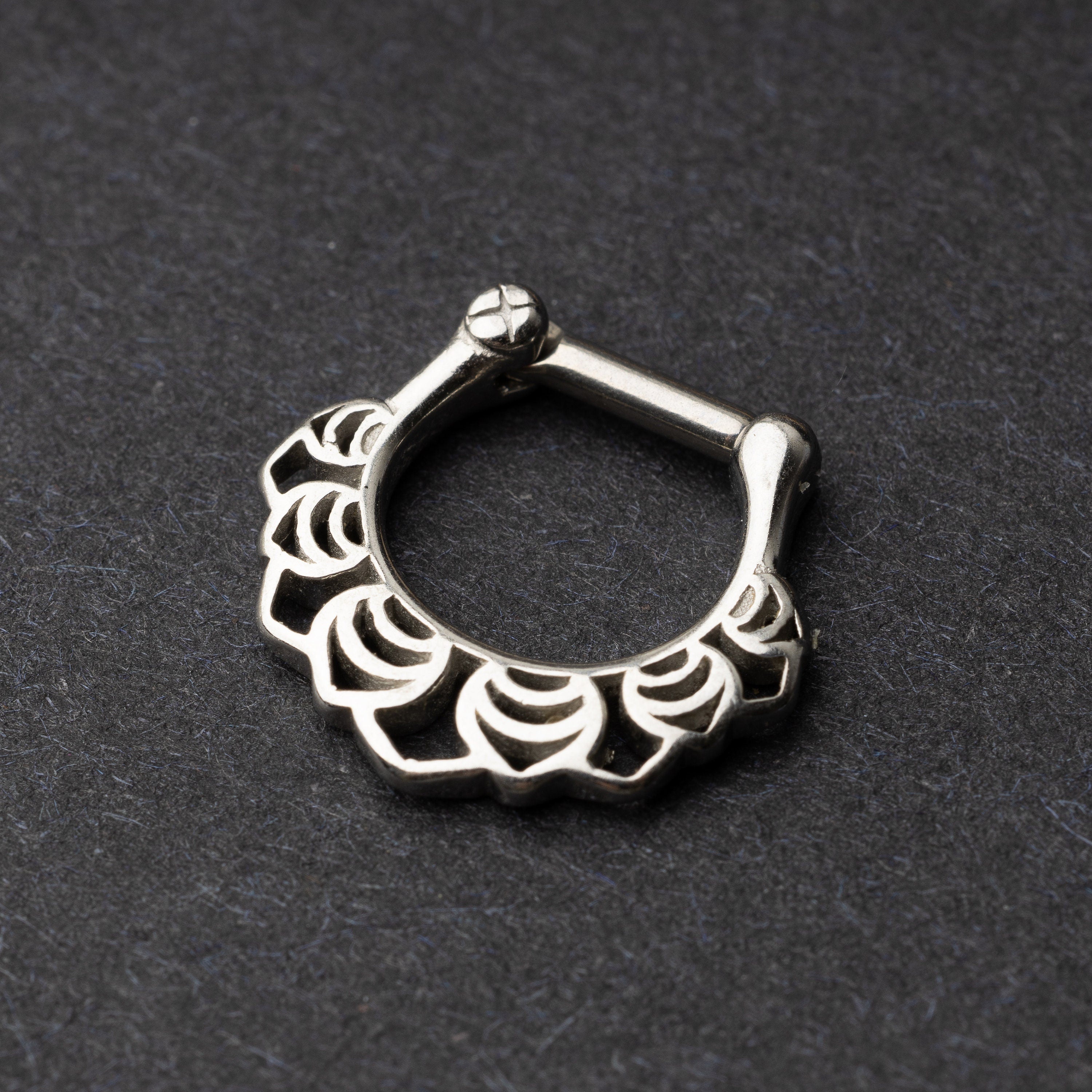 Close-up of a silver septum clicker with an Art Deco-inspired scalloped design, displayed on a dark background with a secure hinged clasp.