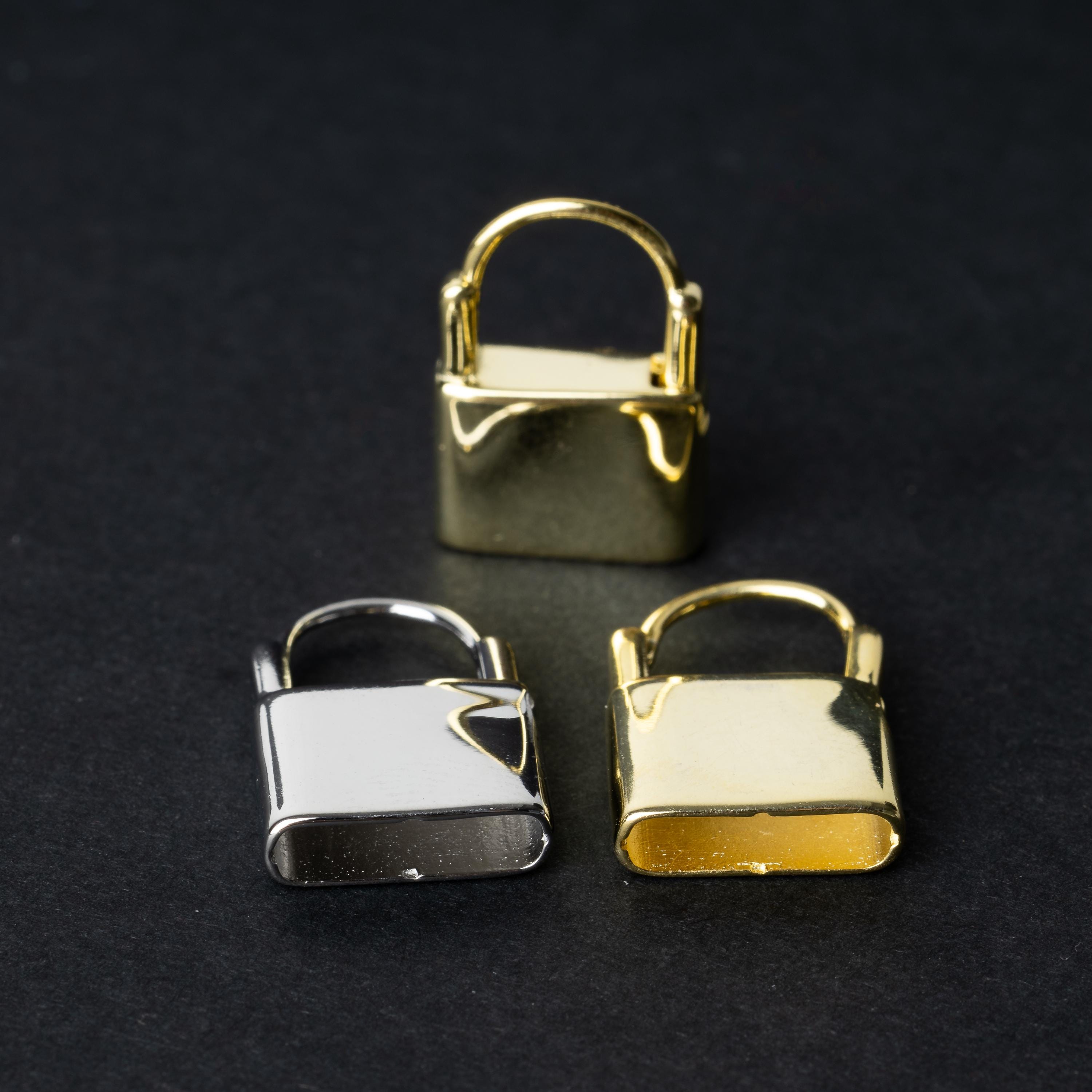 Two padlock-shaped earrings made from 925 sterling silver, one in a gold-tone and the other in silver-tone, displayed on a dark background.