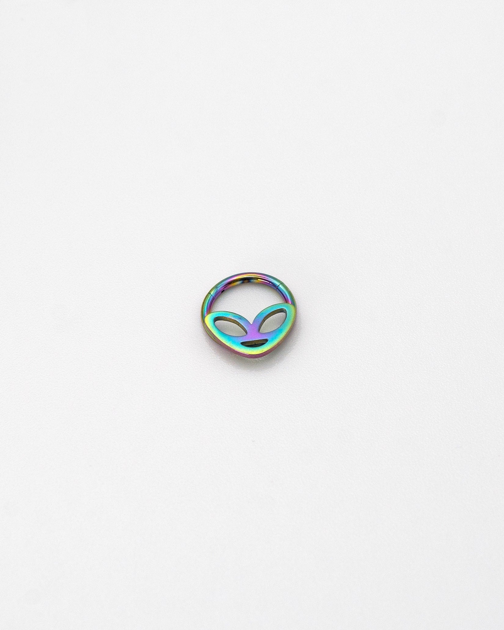 Alien-themed septum clicker in rainbow finish, displayed on a white background.