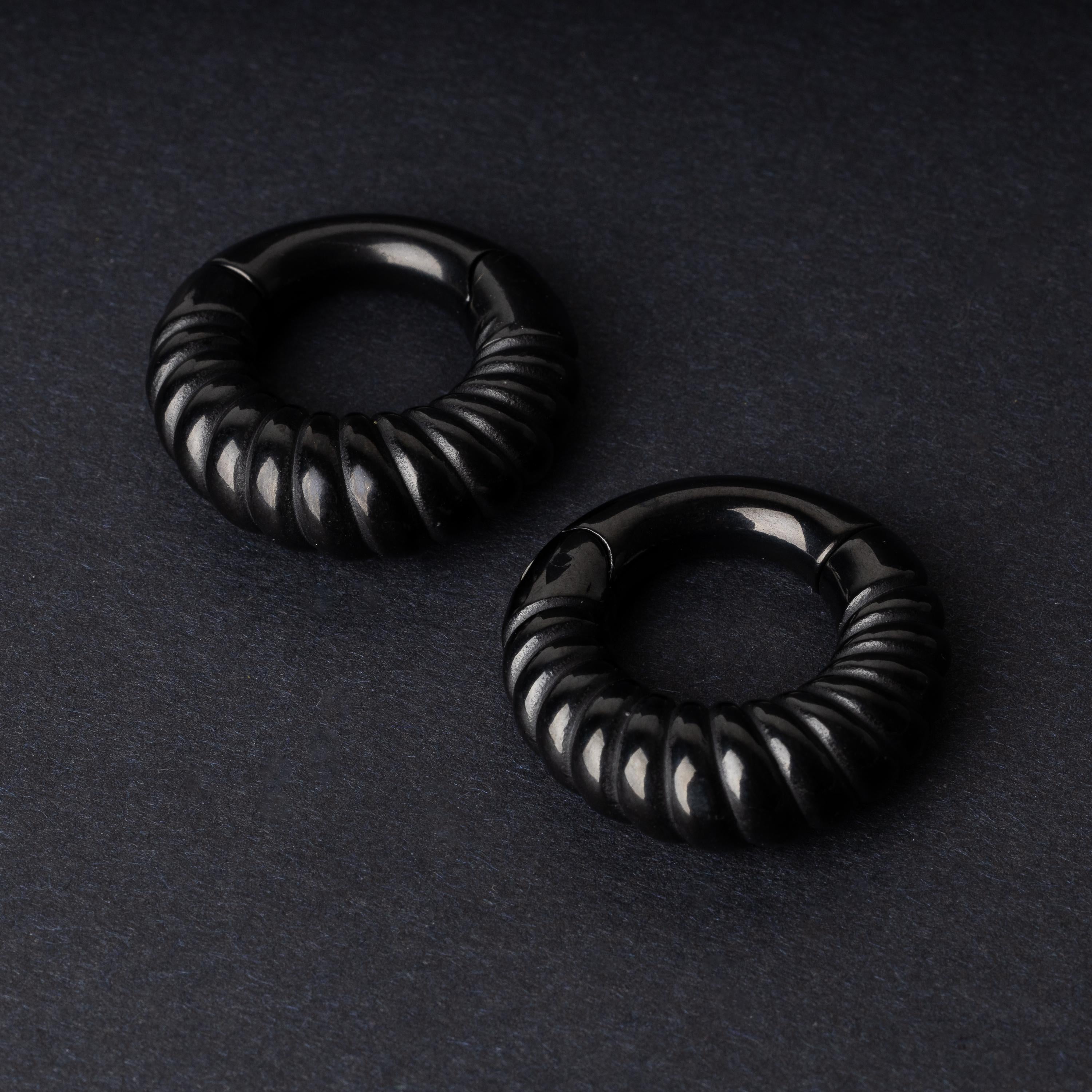 Black textured hoop rings with a ridged design on a dark background.