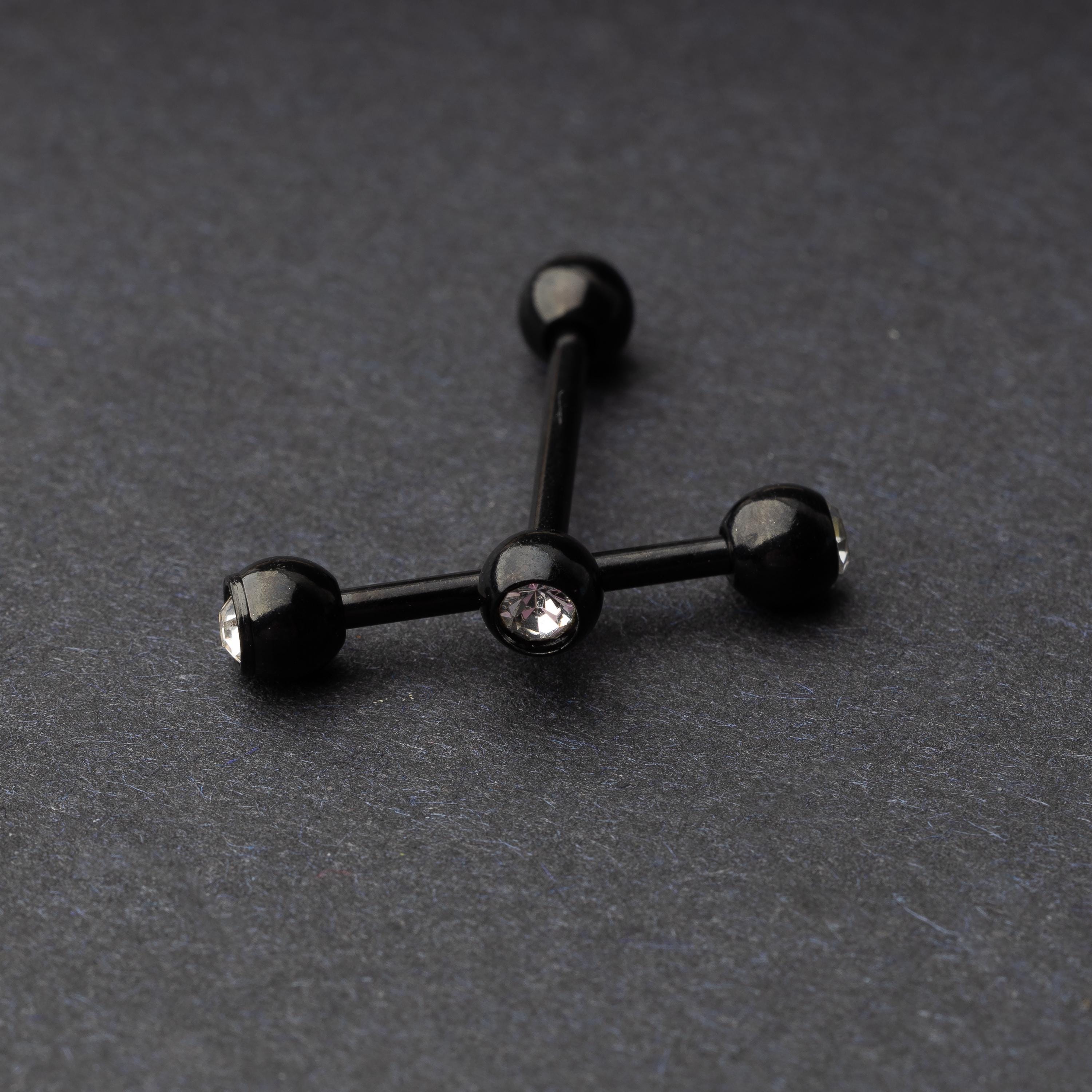 A set of black stainless steel nipple bars with polished gem-studded ends, displayed on a dark background.