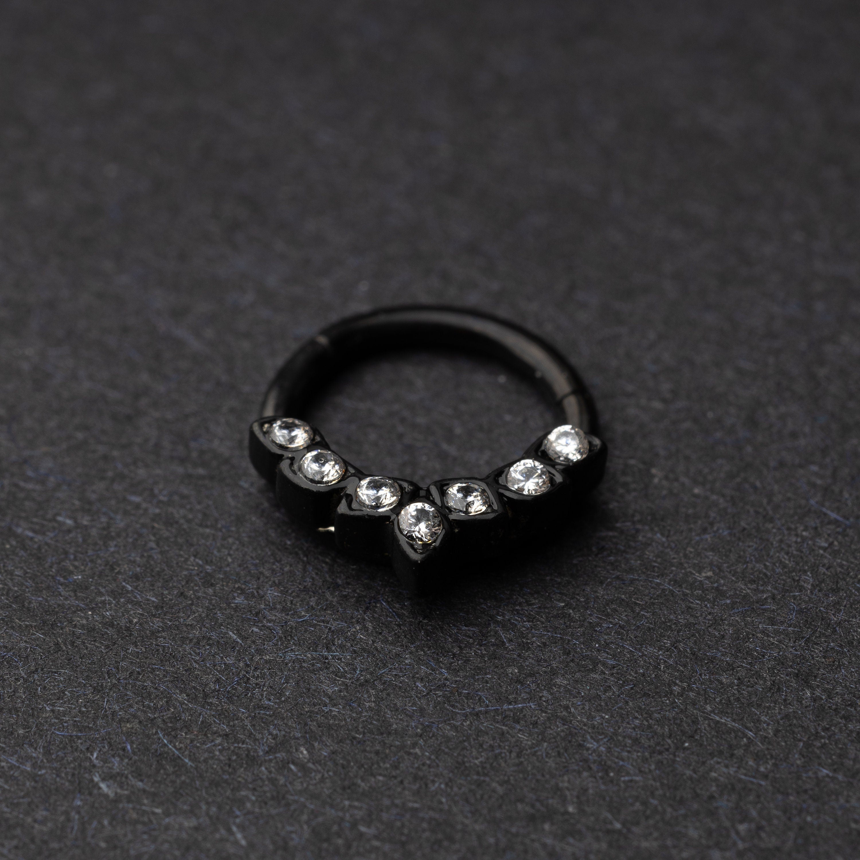 Marquise gemstone stainless steel clicker in black displayed on a dark textured background.