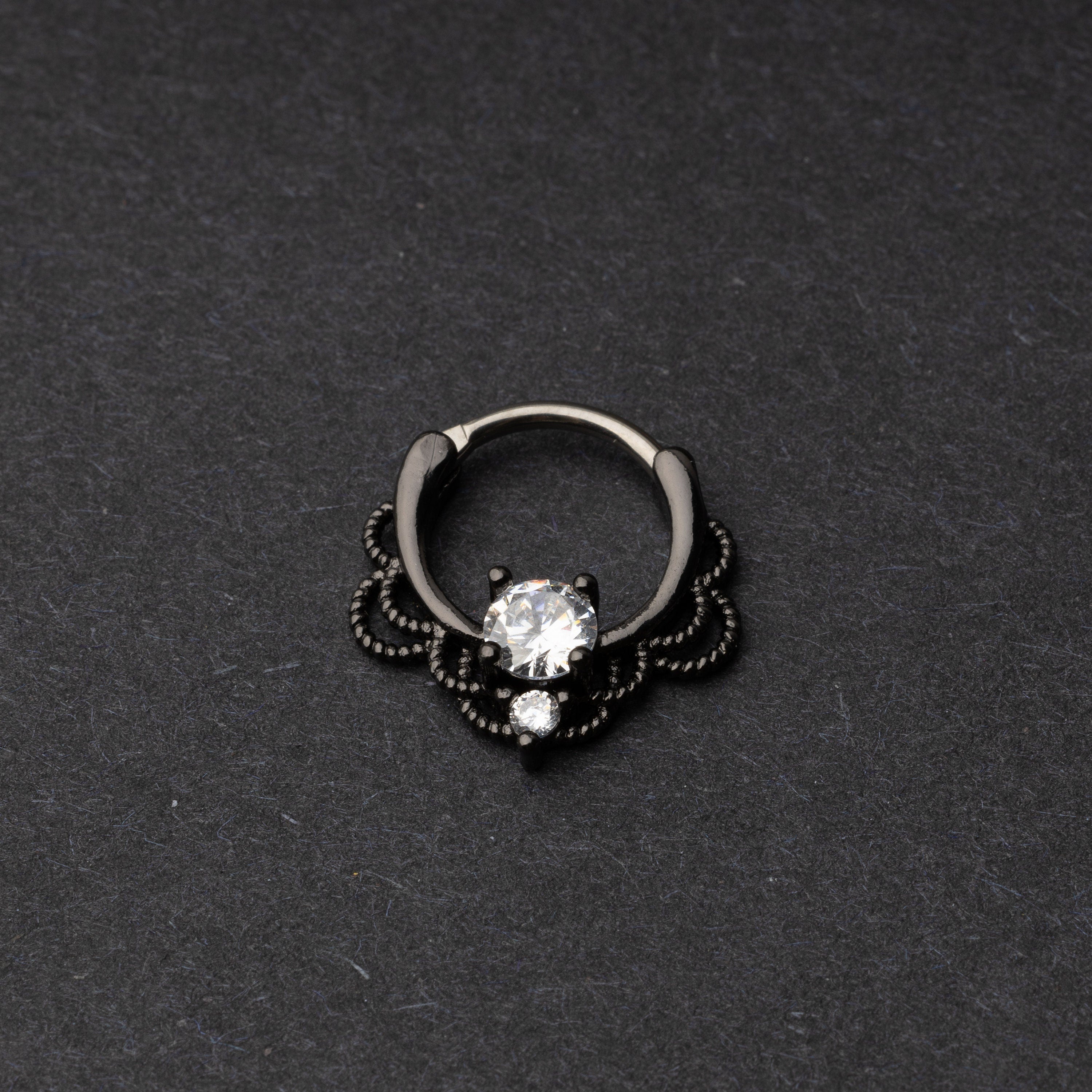 Black Ornate Jewelled Septum Clicker with a clear gem on a dark background