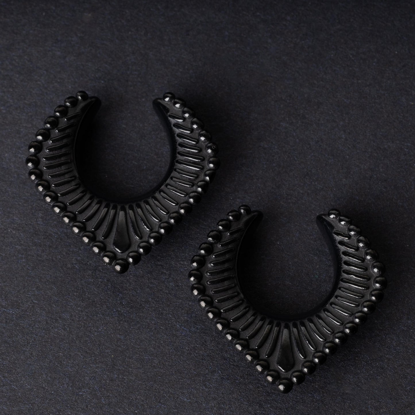 Black saddle hangers on a dark textured background.