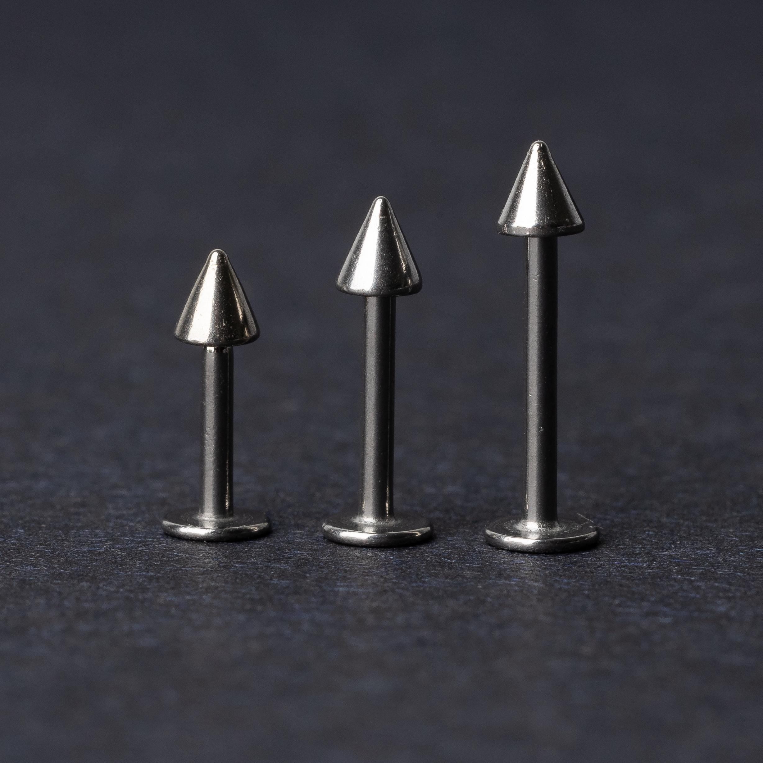 Three stainless steel flat-back barbells with spiked ends, displayed on a dark background showcasing their polished and sleek design.