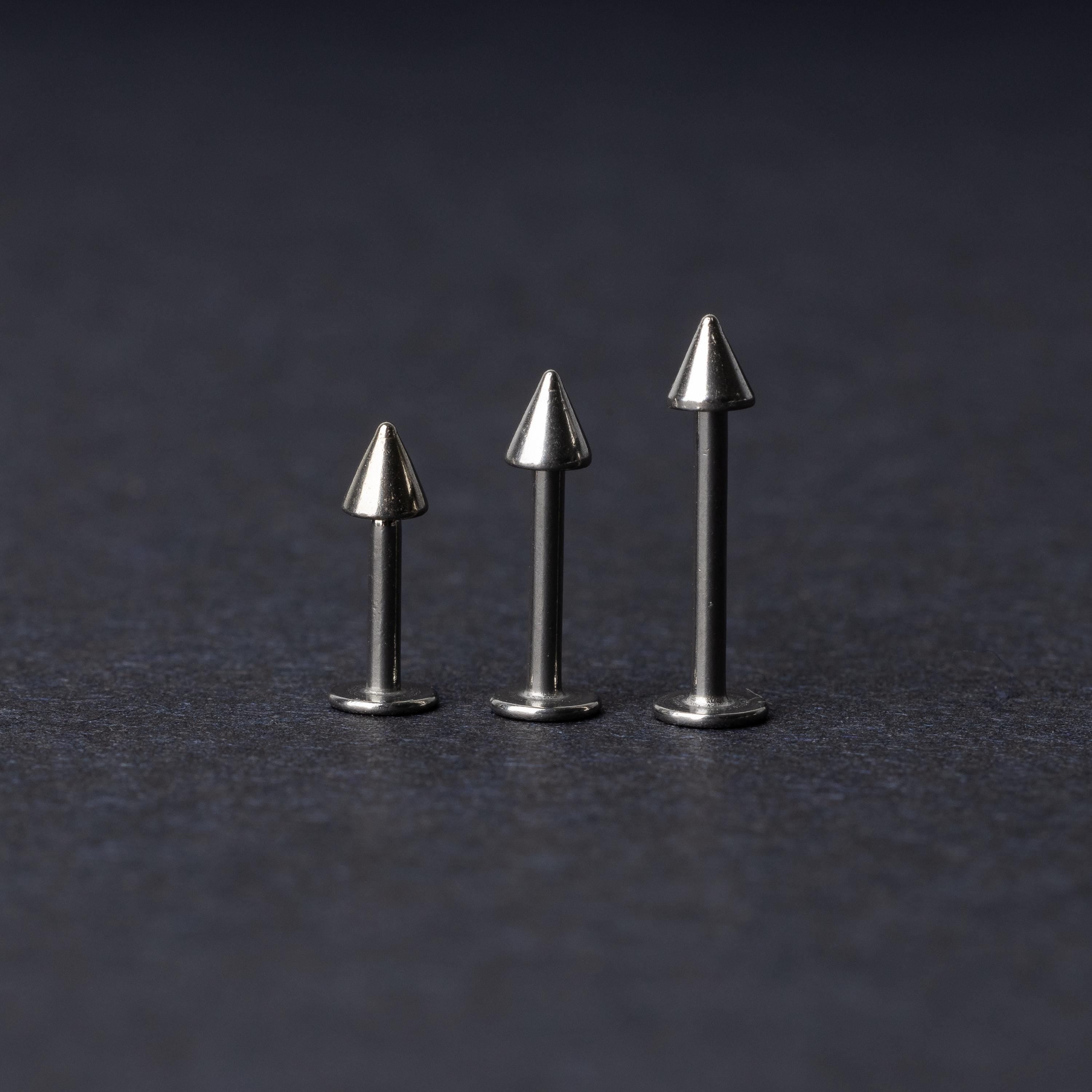 Three stainless steel flat-back barbells with spiked ends, displayed on a dark background showcasing their polished and sleek design.