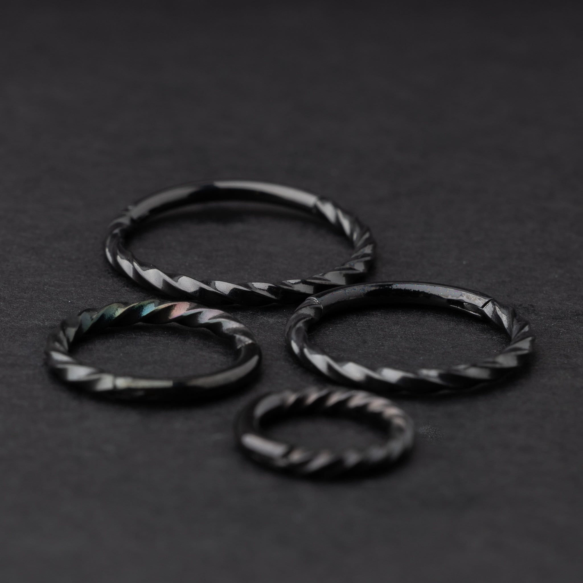 Black twisted clicker rings in varying sizes, displayed on a dark background.