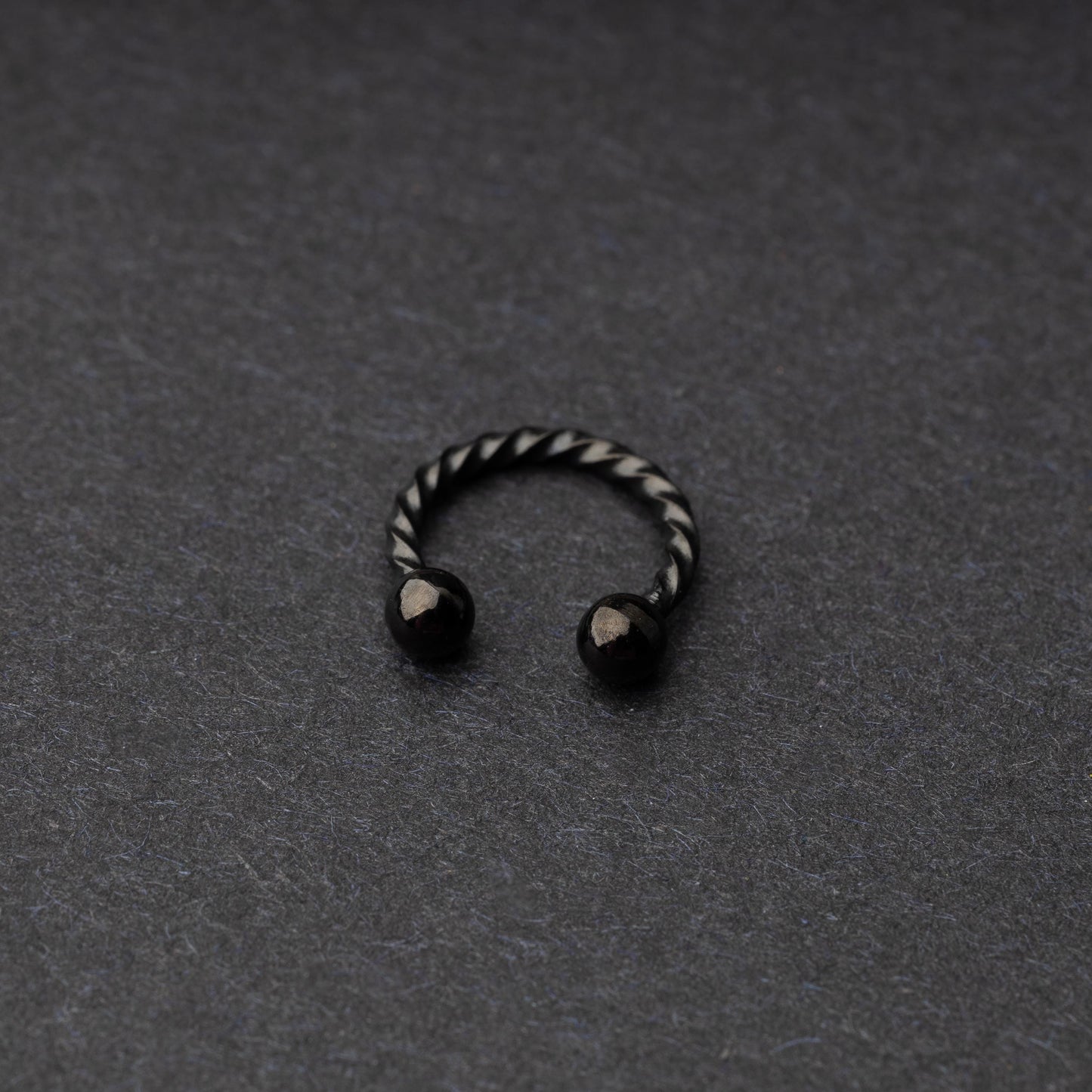 Twisted horseshoe barbells in black finish displayed on a dark background, highlighting their bold and unique design.