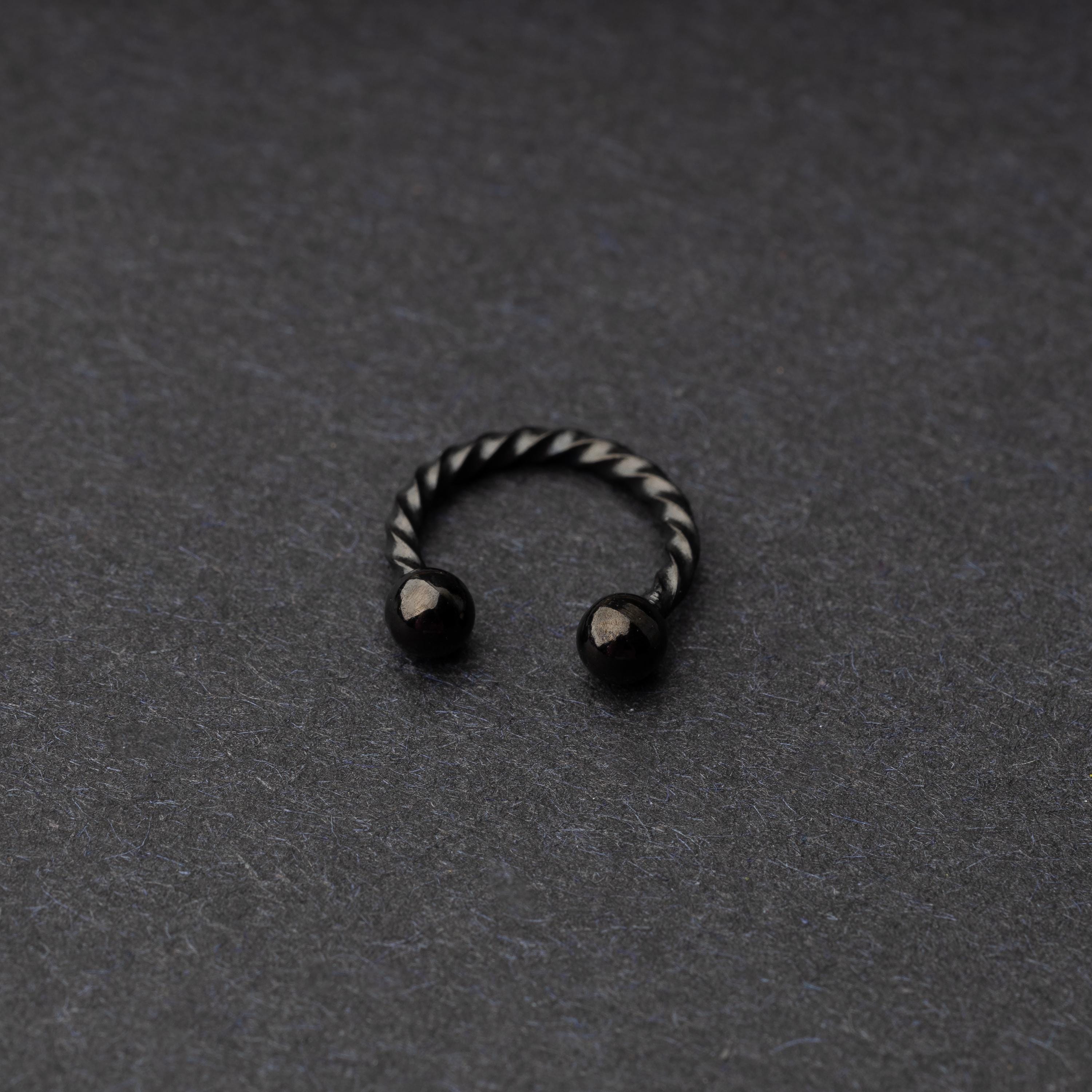 Twisted horseshoe barbells in black finish displayed on a dark background, highlighting their bold and unique design.