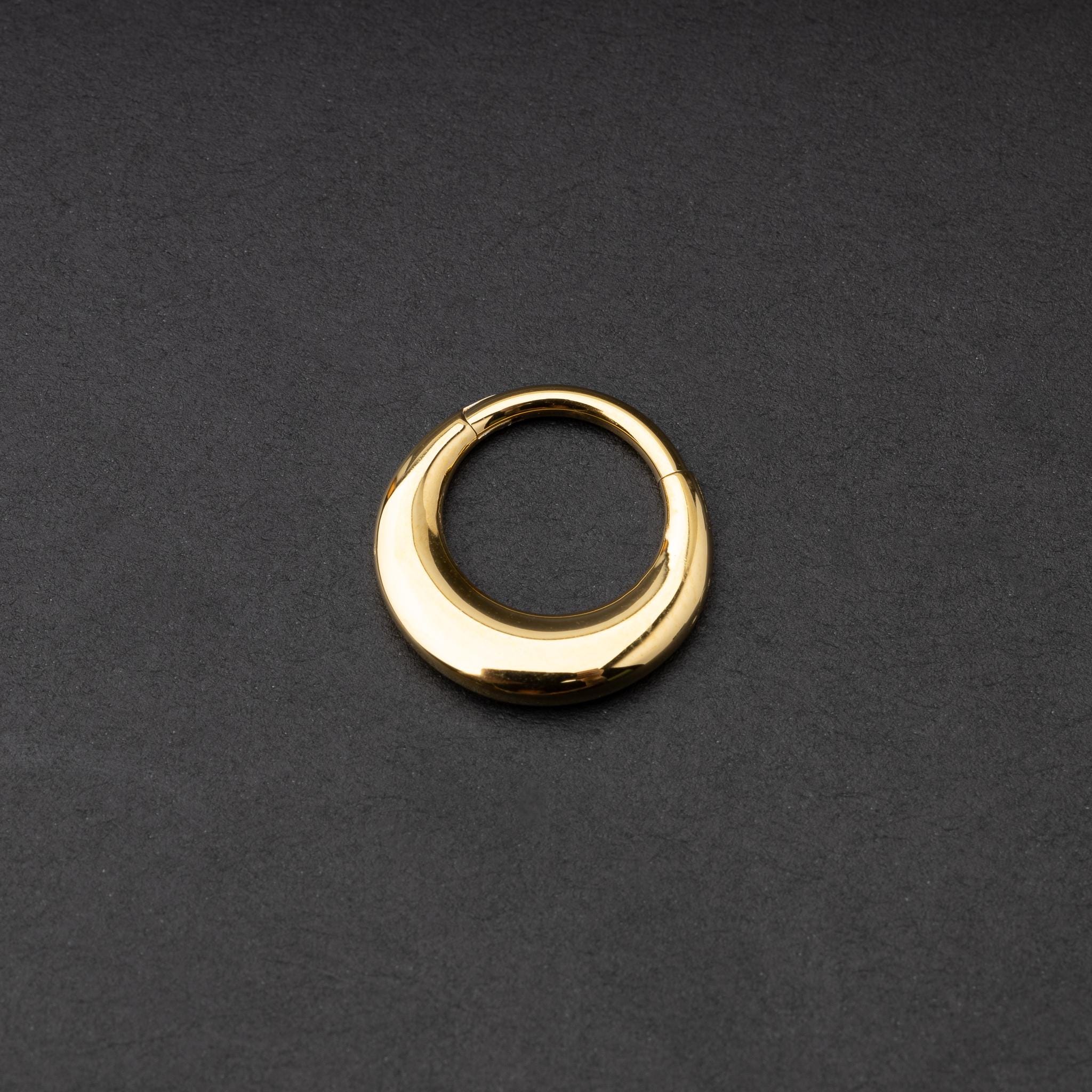 Crescent-shaped septum clicker in gold, with a polished finish, displayed on a dark background.
