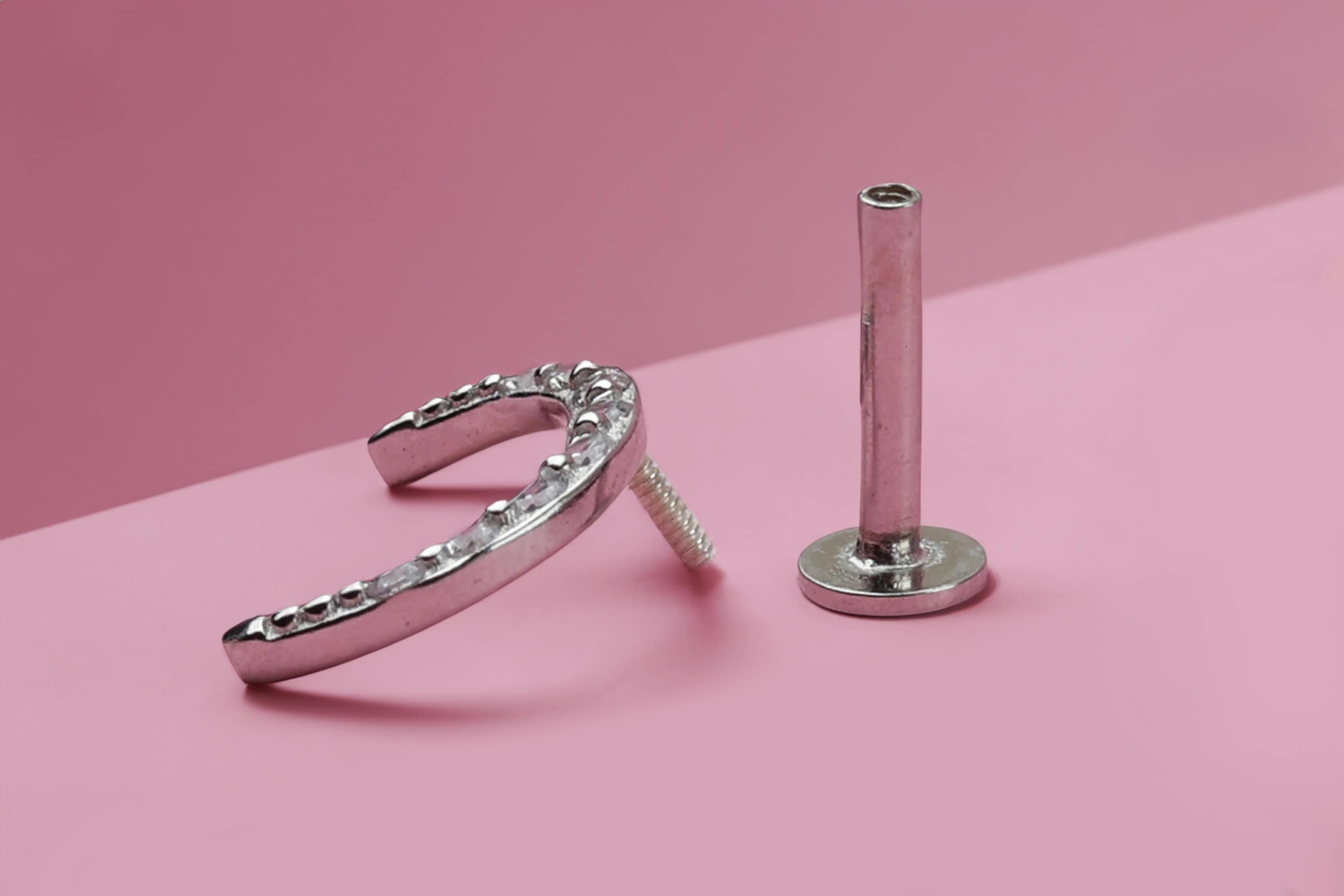 Crescent Moon Labret bar on a pink background.