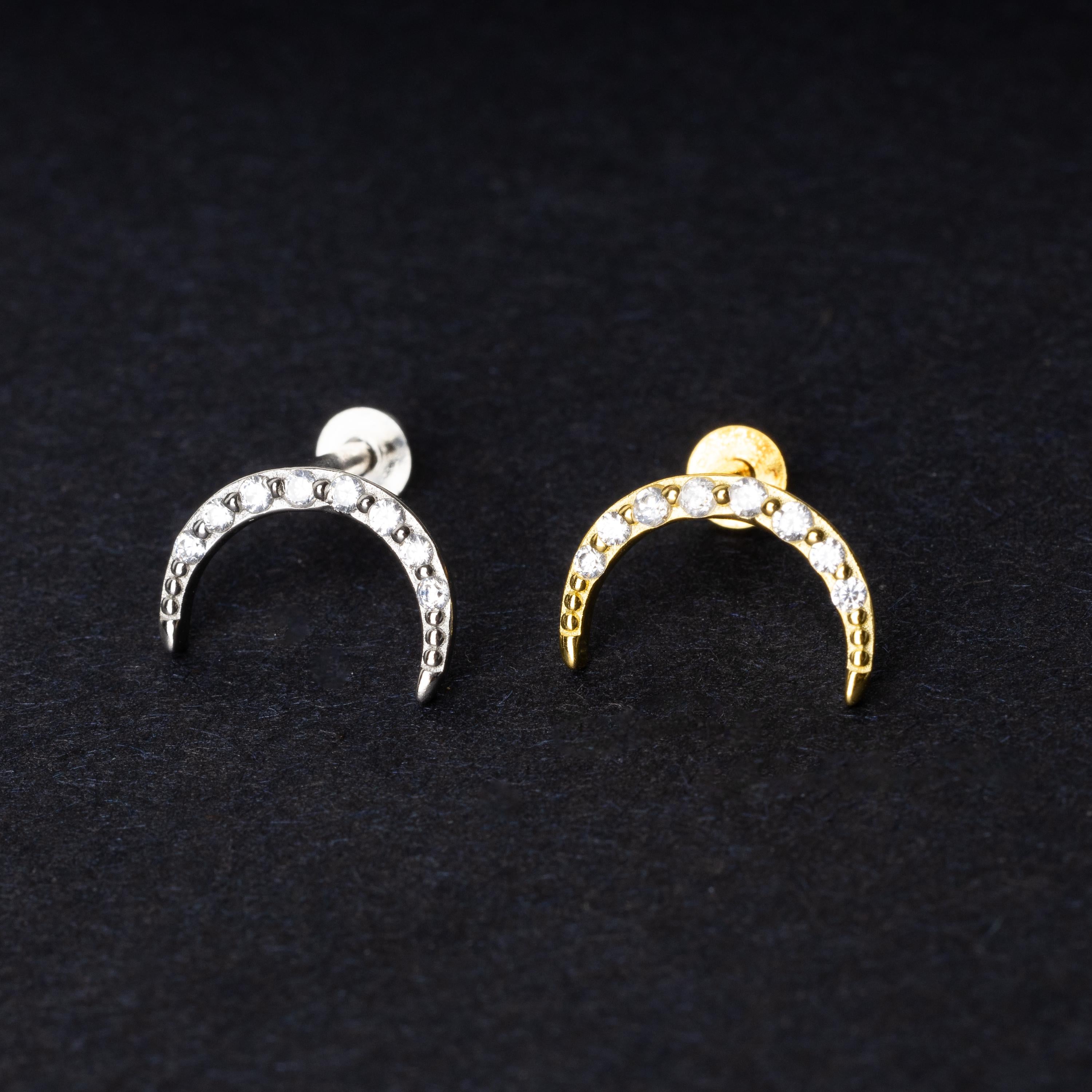 Close-up of gold and silver crescent moon stud earrings featuring CZ gems, displayed on a dark background.