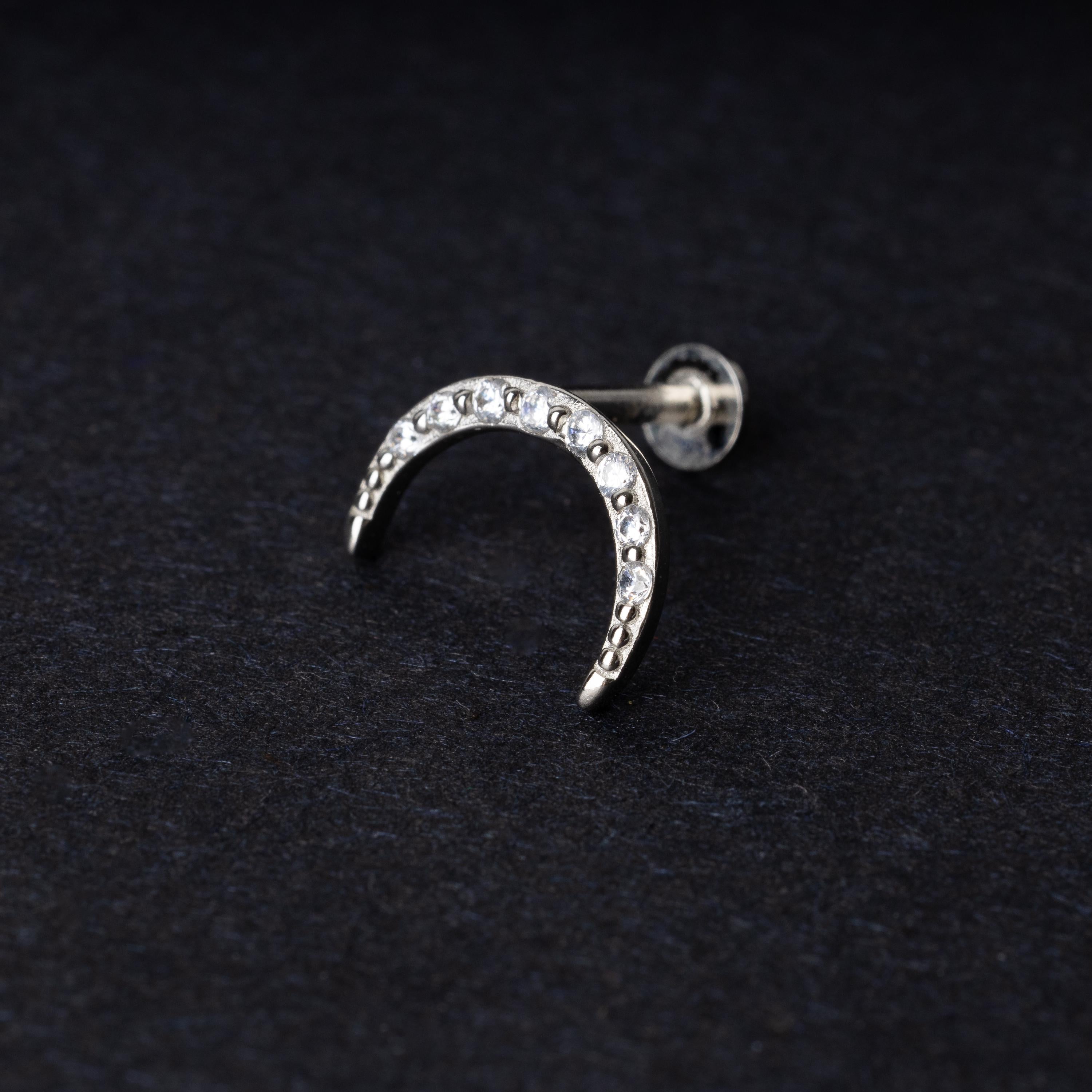 Silver crescent moon stud earring featuring CZ gems, displayed on a dark background.