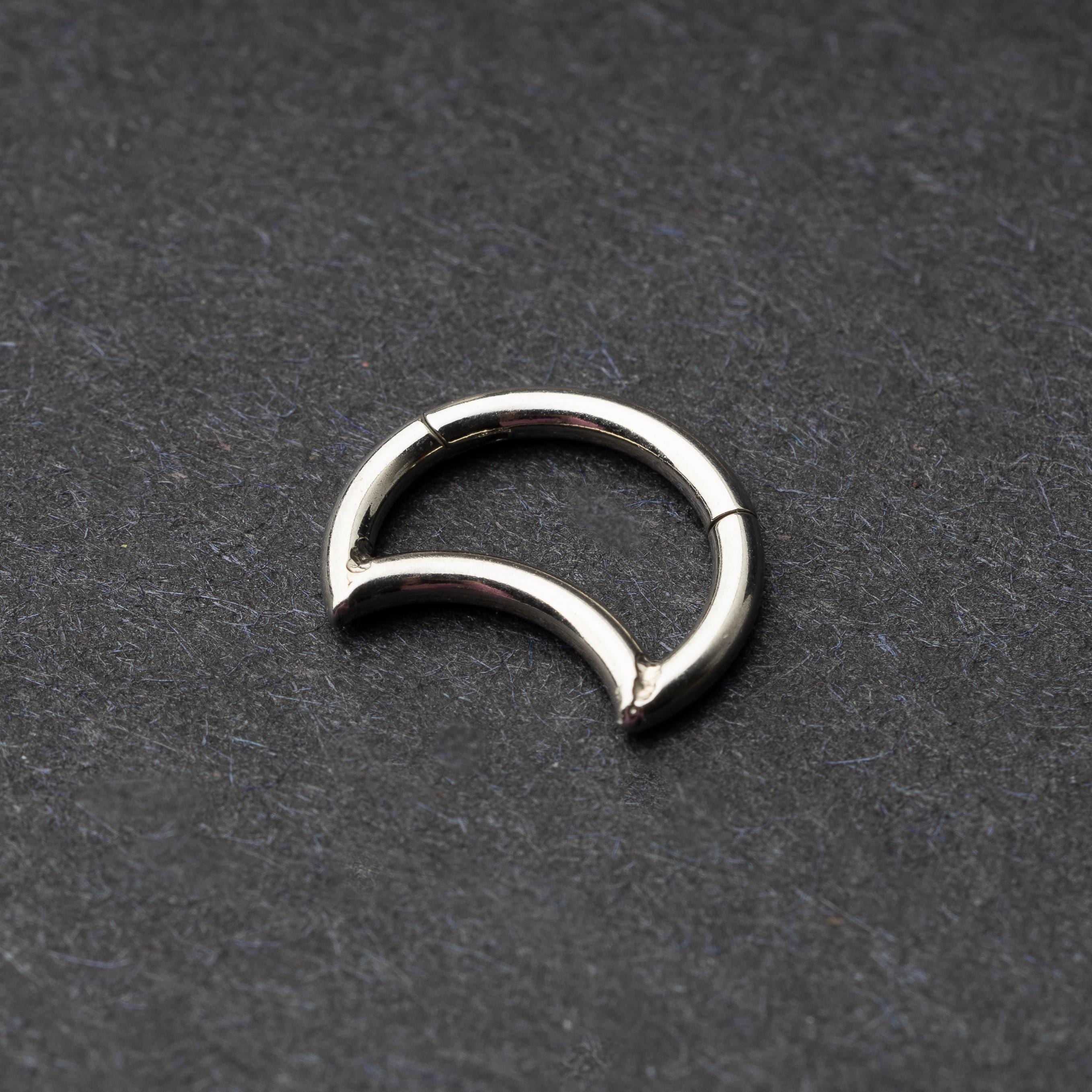 Close-up of a minimalist crescent-shaped clicker made of titanium, displayed on a dark background.