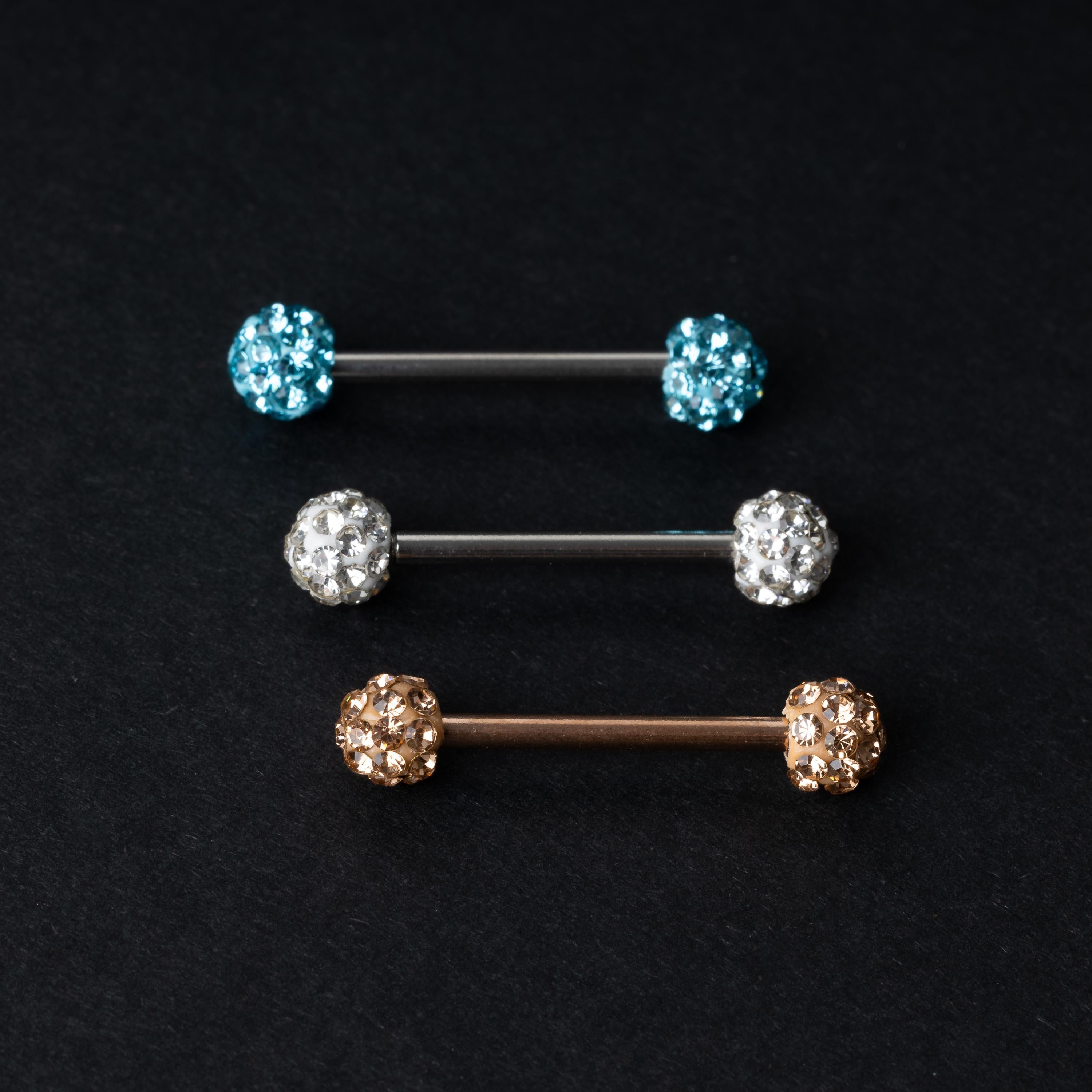 Barbells with textured crystal-encrusted ends in silver, gold, and icy blue finishes, displayed on a dark background.