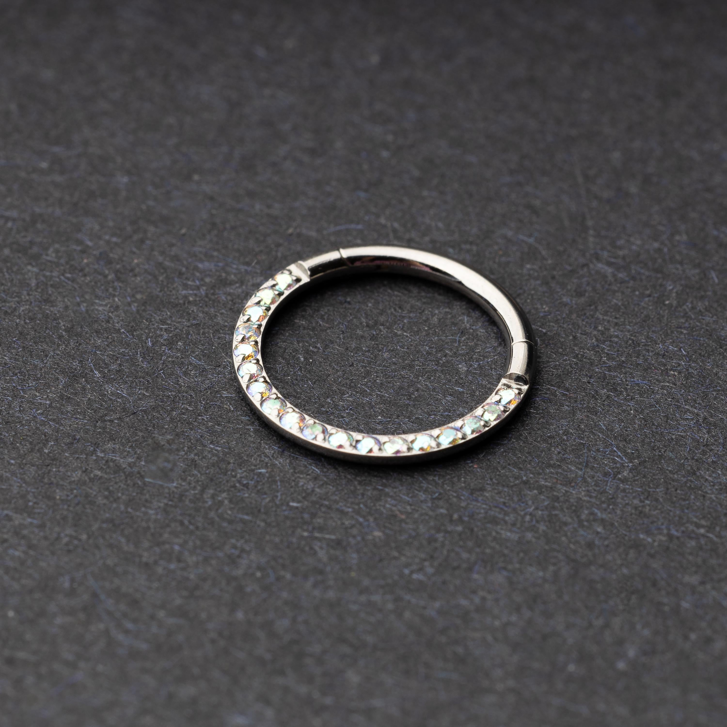 Titanium clicker ring with iridescent crystals, displayed on a dark background.