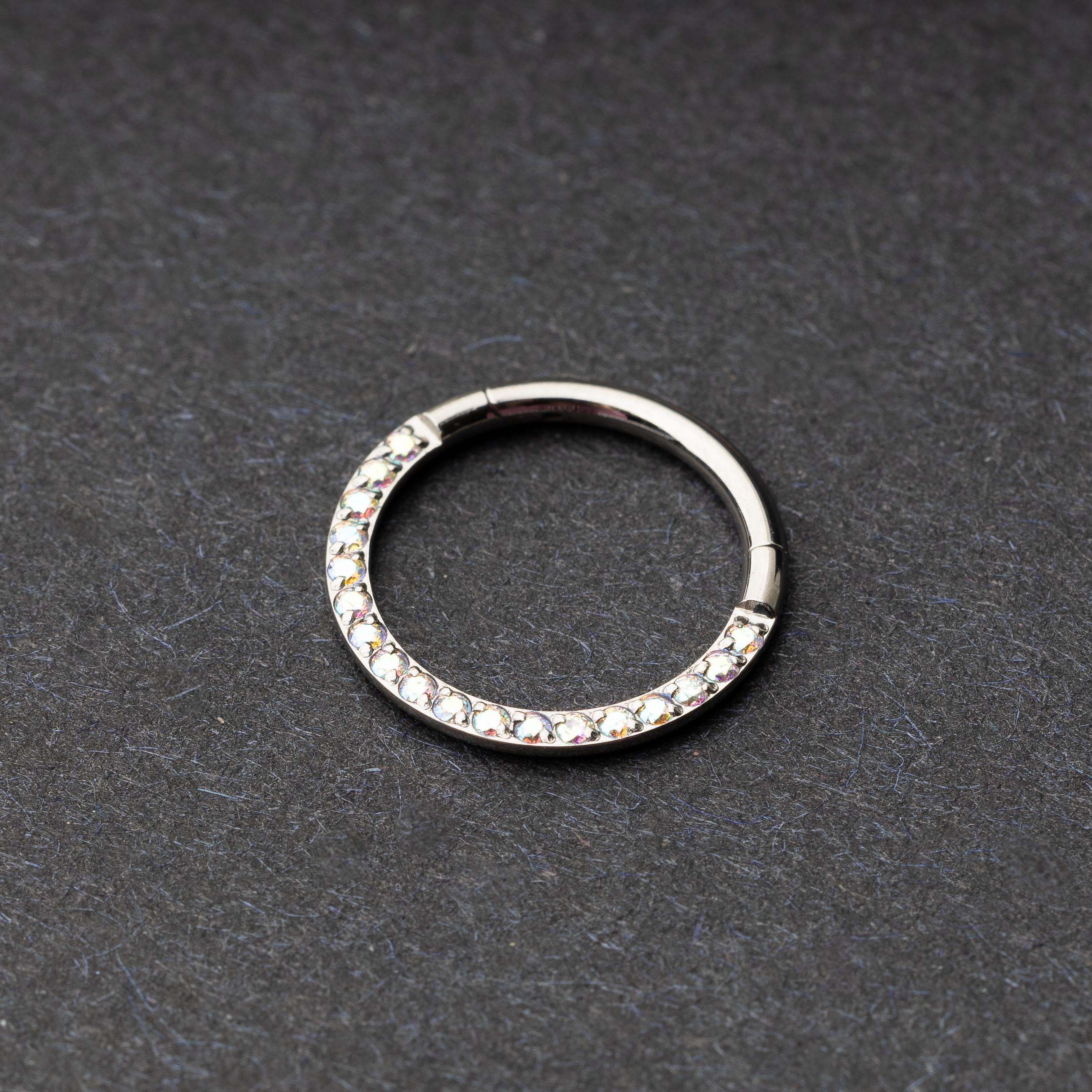 Titanium clicker ring with iridescent crystals, displayed on a dark background.