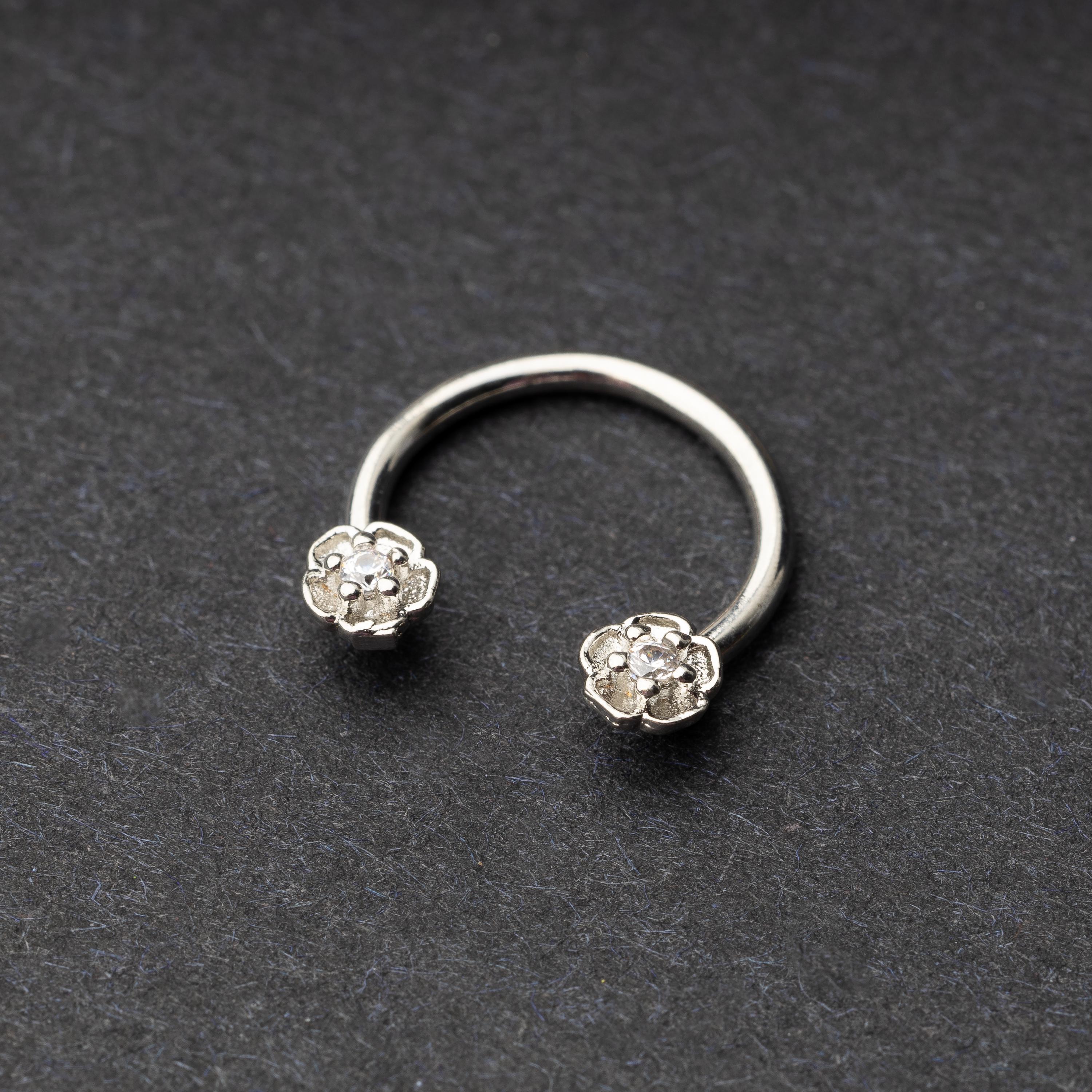 Horseshoe hoop featuring a flower charm, displayed on a dark background.