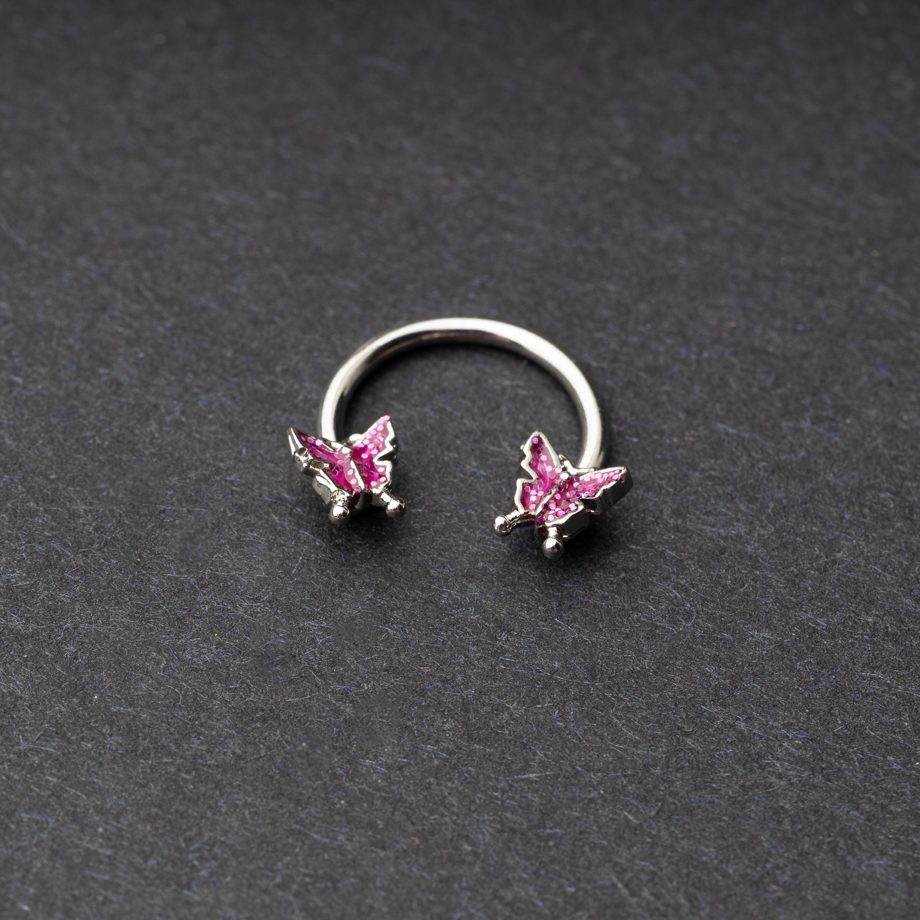 Horseshoe hoop featuring a butterfly charm, displayed on a dark background.