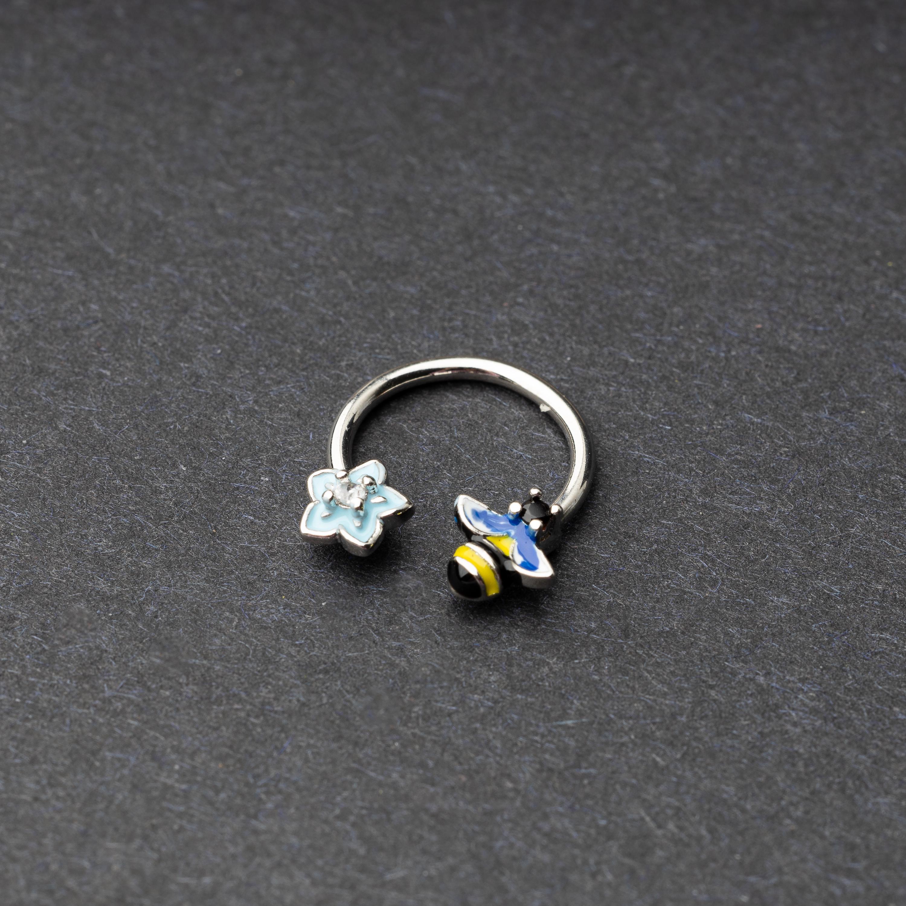 Horseshoe hoop featuring bee and flower charms, displayed on a dark background.