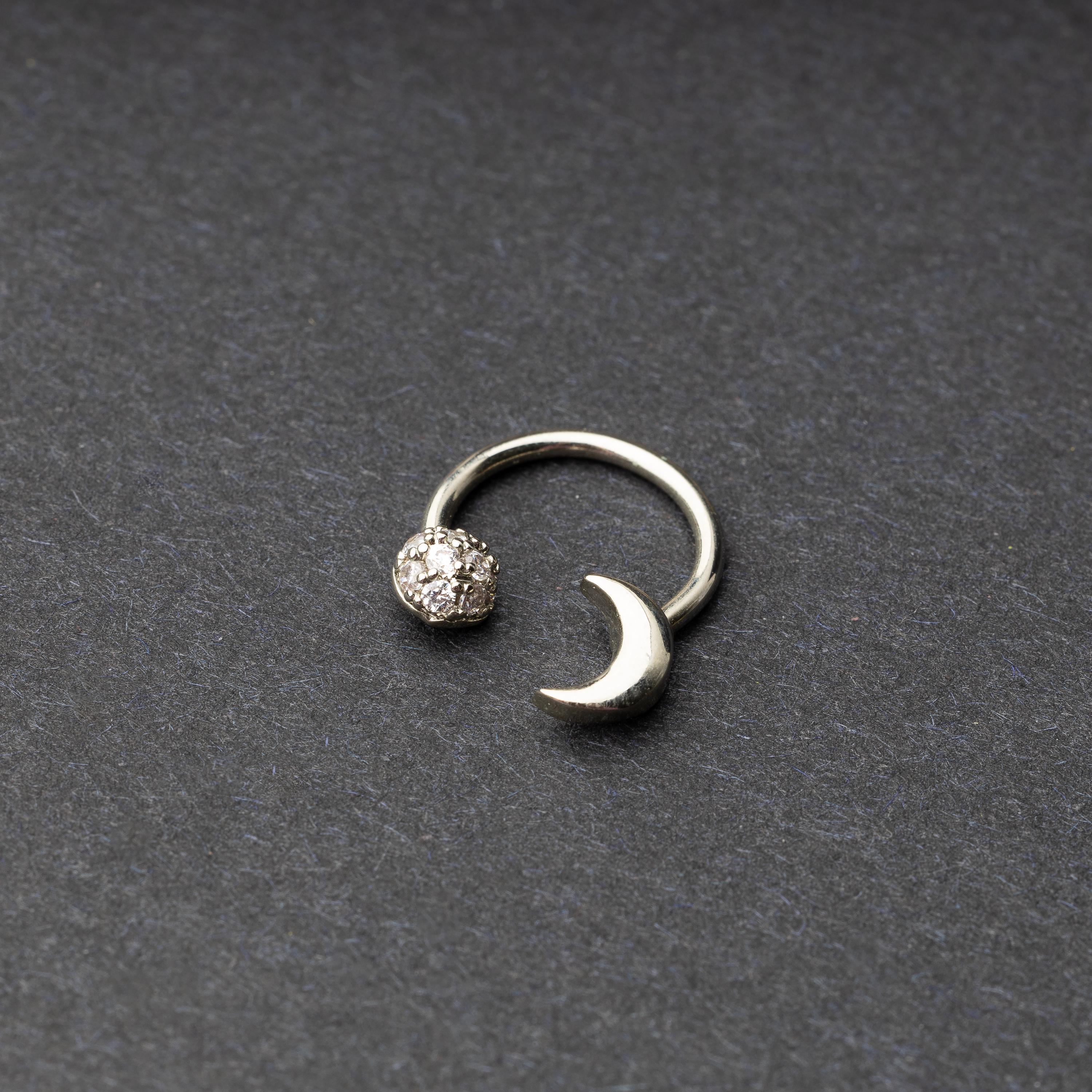 Horseshoe hoop featuring moon charms, displayed on a dark background.