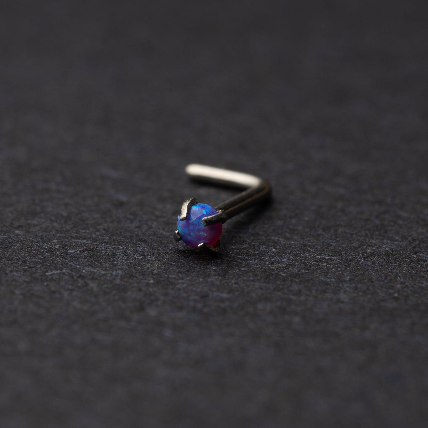 Opal L shaped nose stud on a dark background