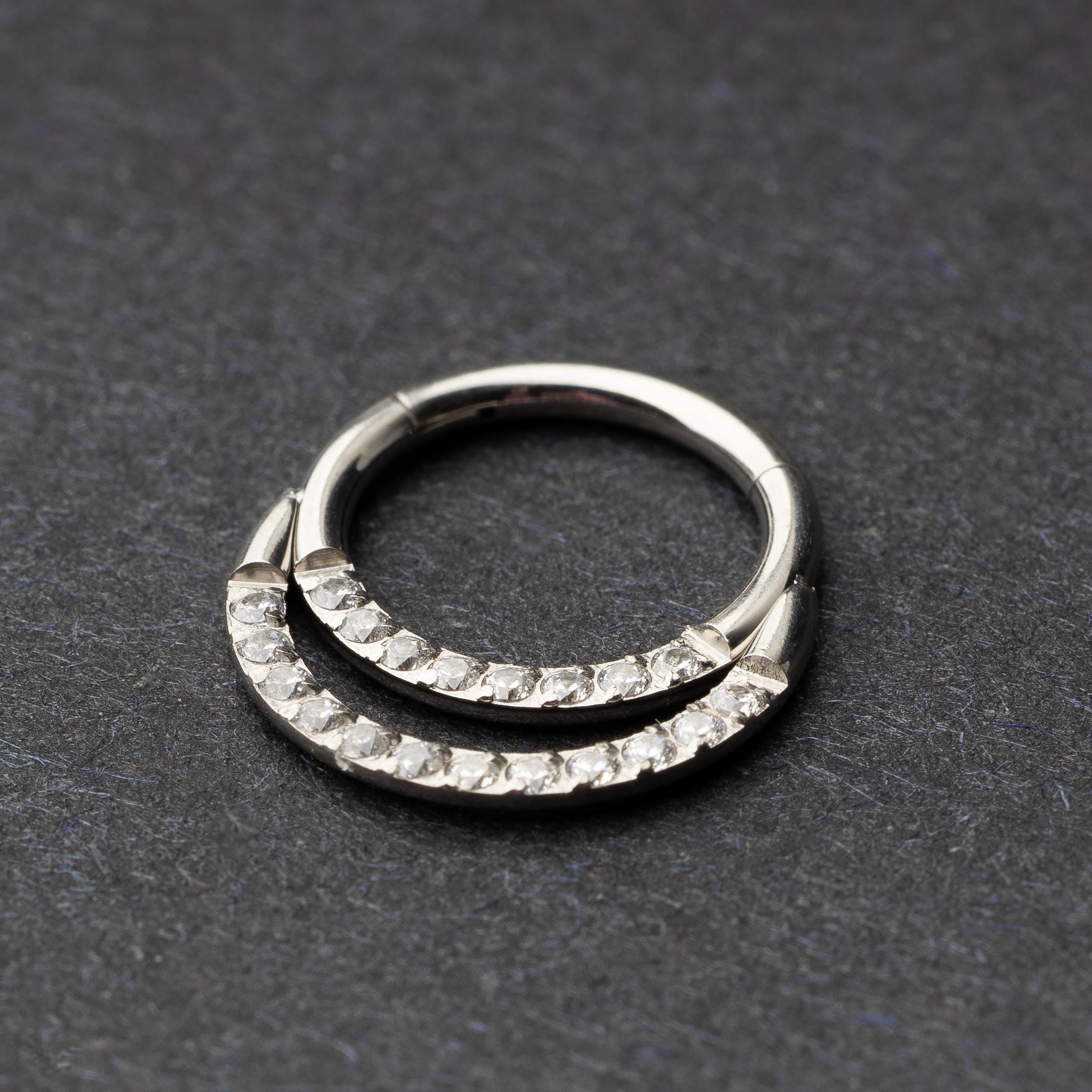 Titanium double-layered clicker with sparkling cubic zirconia accents, displayed on a dark background.