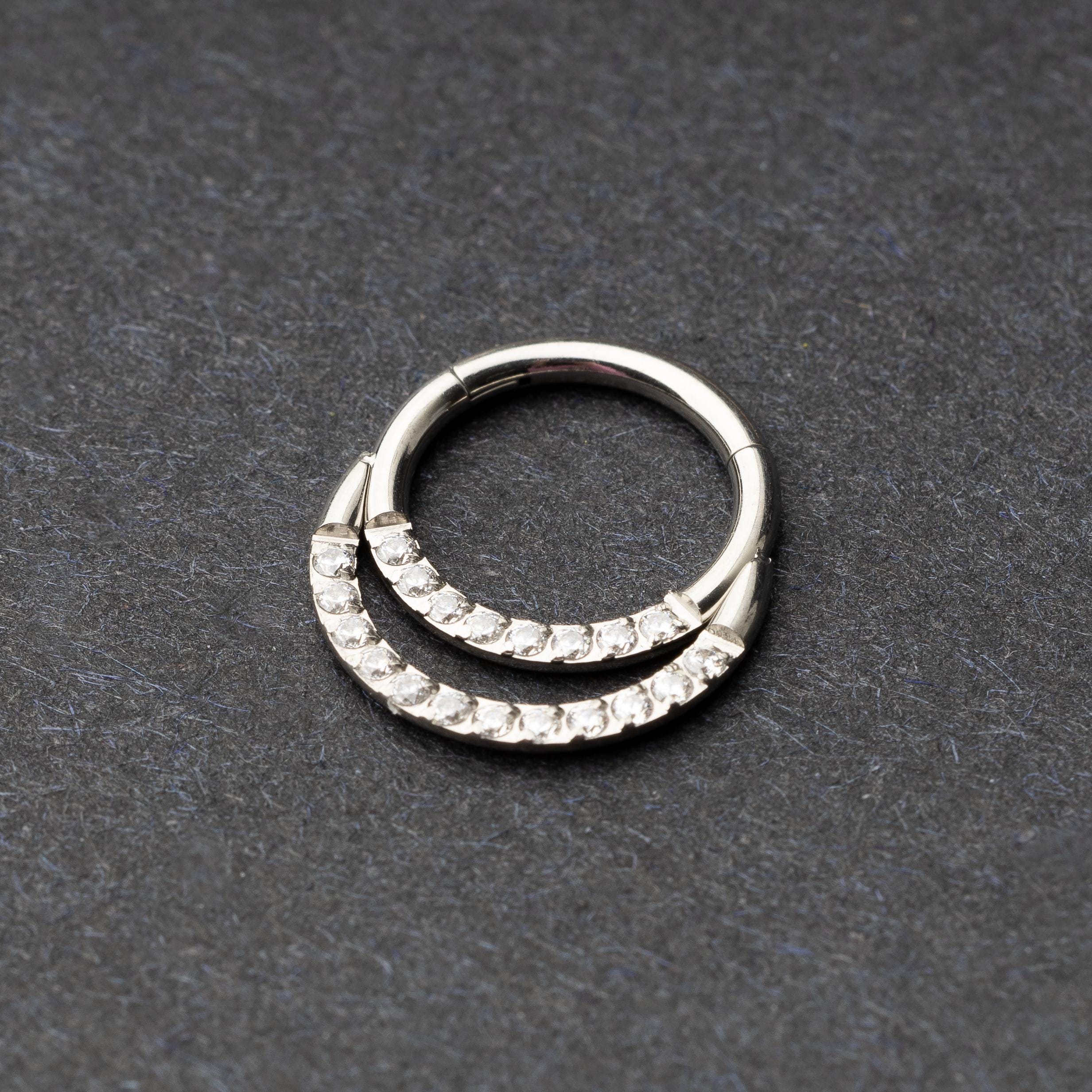 Titanium double-layered clicker with sparkling cubic zirconia accents, displayed on a dark background.