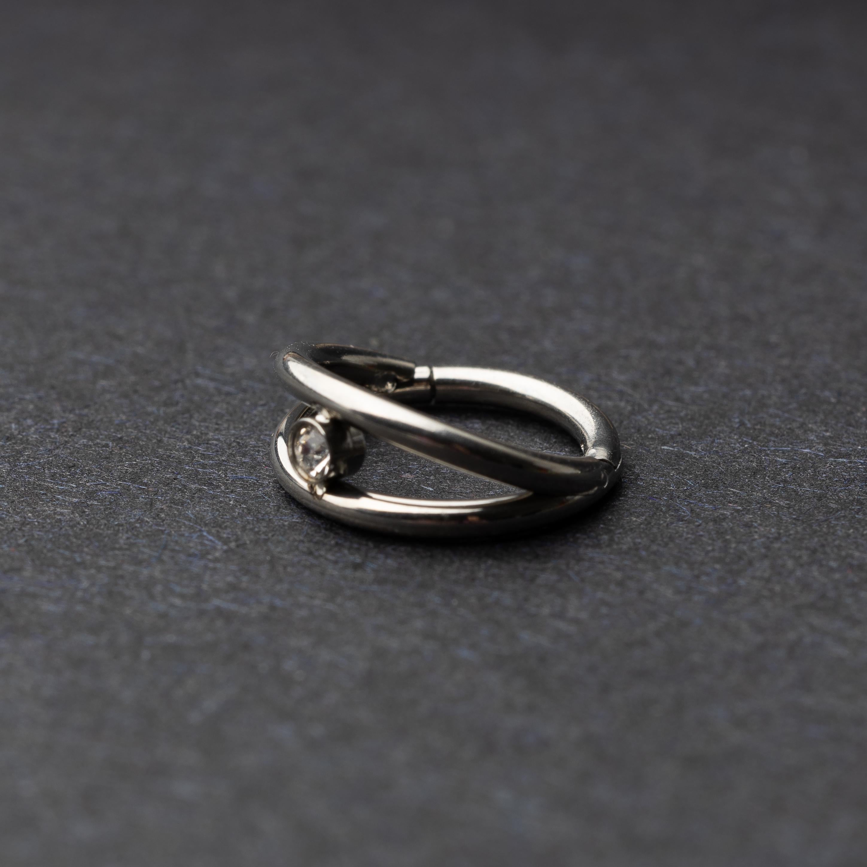 Titanium clicker with a double-layered design and a single cubic zirconia, displayed on a dark background.