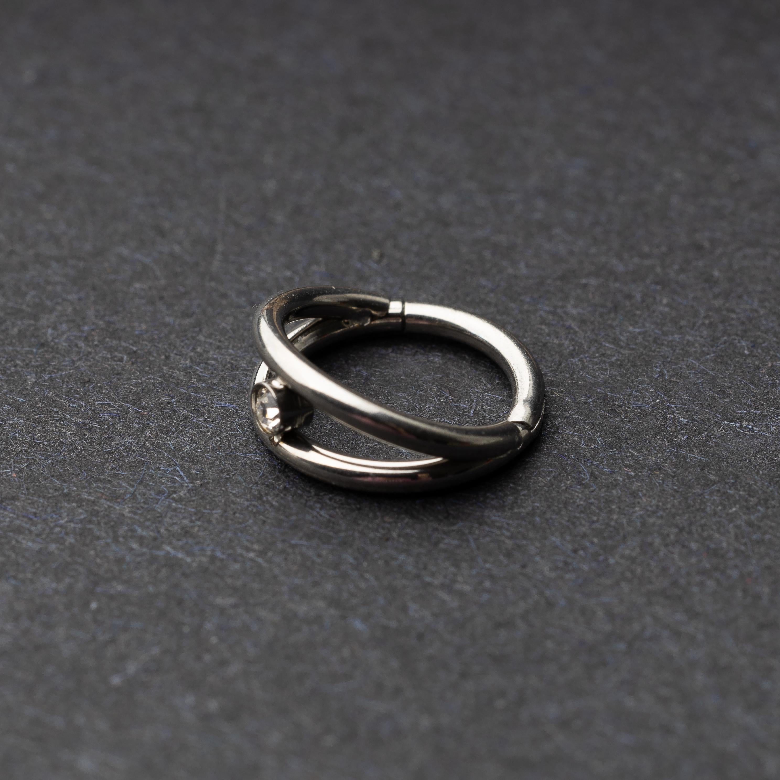 Titanium clicker with a double-layered design and a single cubic zirconia, displayed on a dark background.