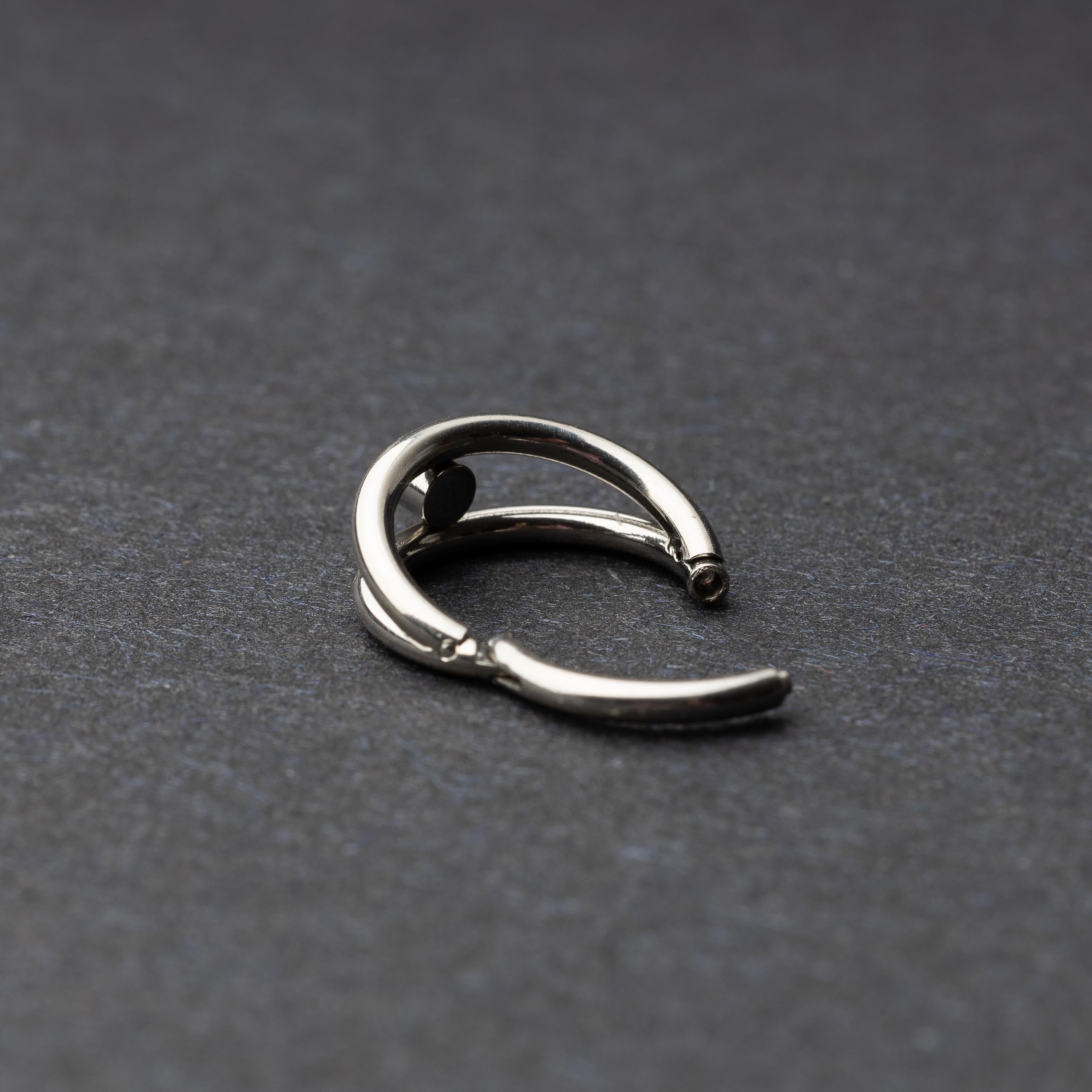 Titanium clicker with a double-layered design and a single cubic zirconia, displayed on a dark background.
