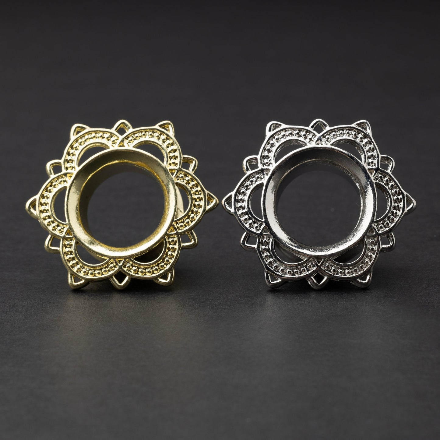 Gold and silver flower-shaped tunnels with intricate detailing, displayed on a dark background.