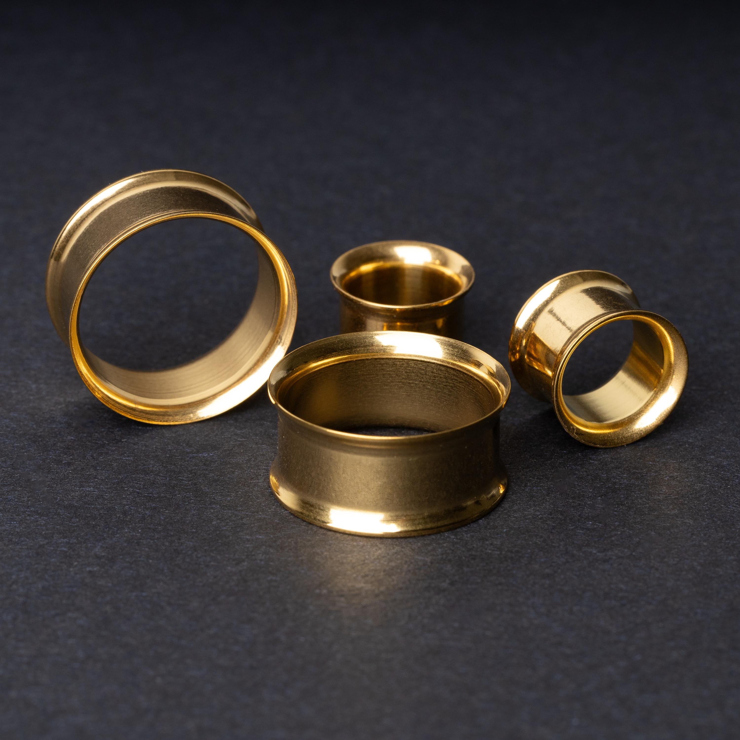 Gold double-flared tunnels in varying sizes, with a polished finish, displayed on a dark background.