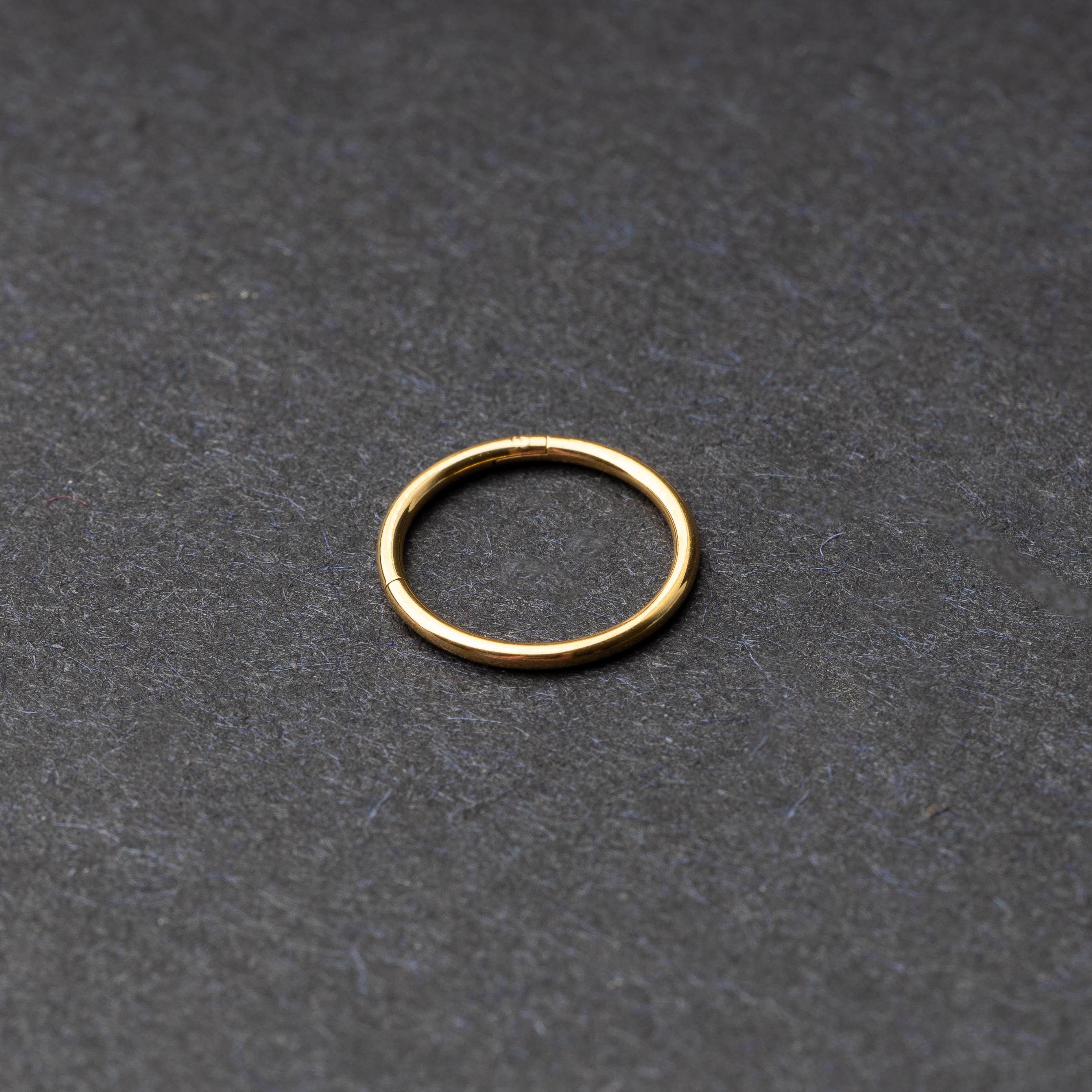 Gold seamless ring with a minimalist design, displayed on a dark background.