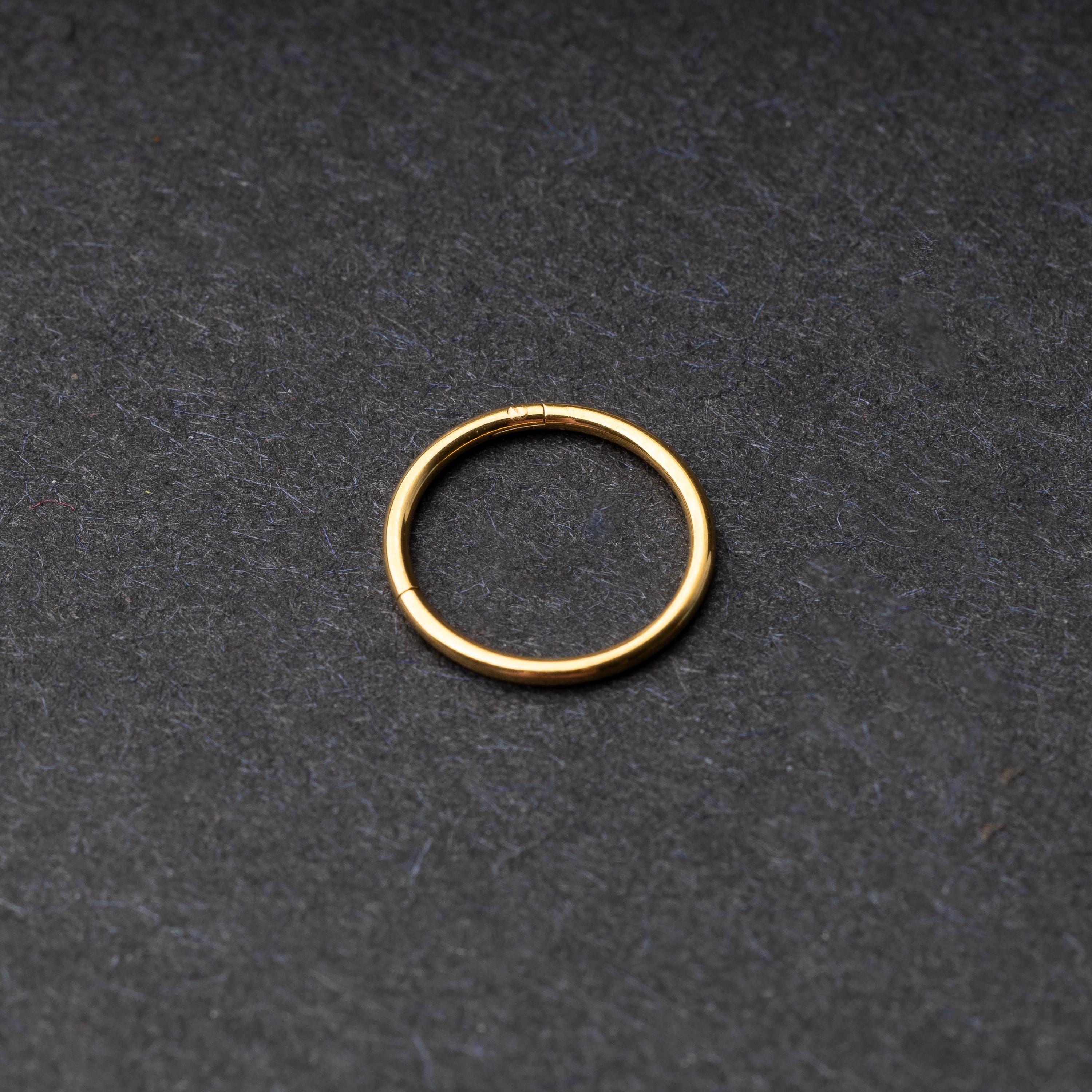 Gold seamless ring with a minimalist design, displayed on a dark background.