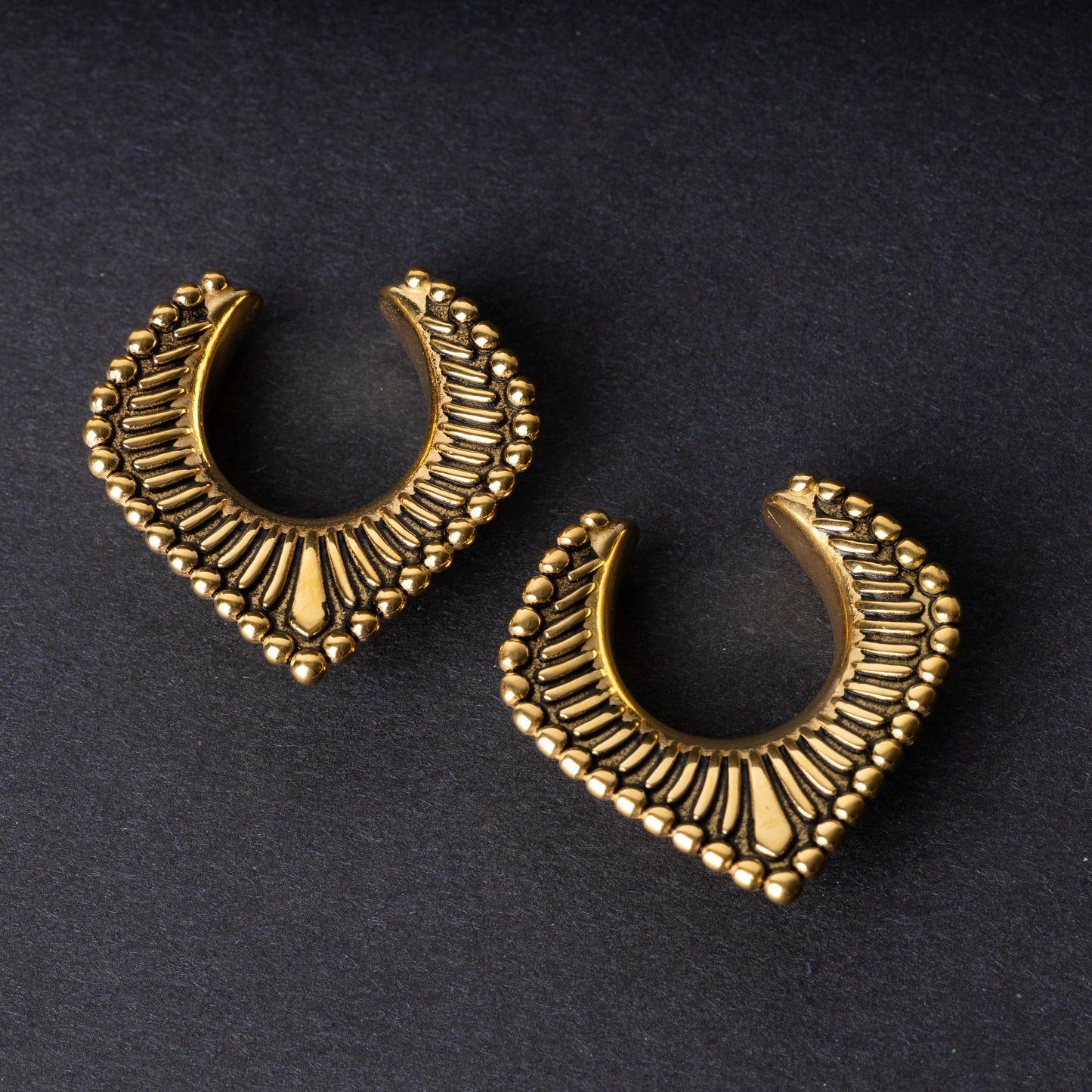 Gold saddle hangers on a dark textured background.