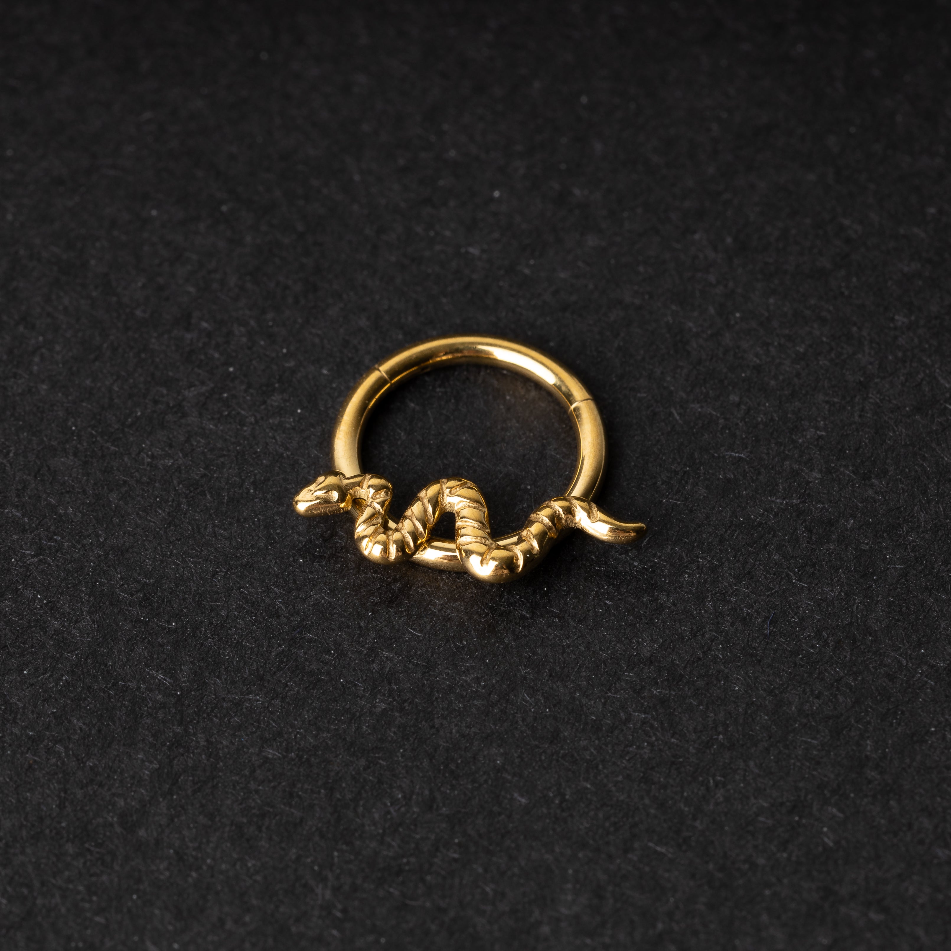 Gold snake clicker ring displayed on a dark background