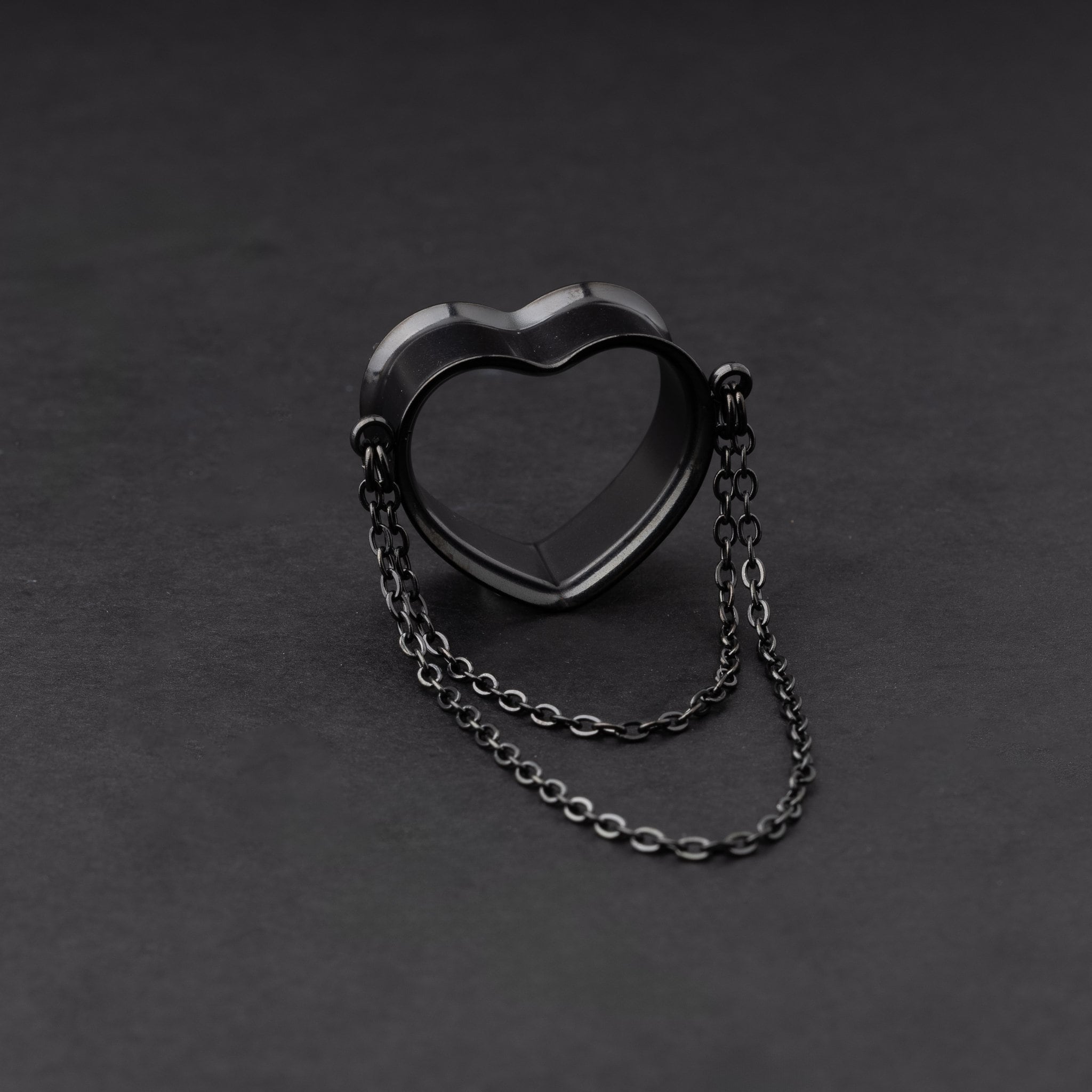 Heart-shaped tunnel with draped chains in black, displayed on a dark background.