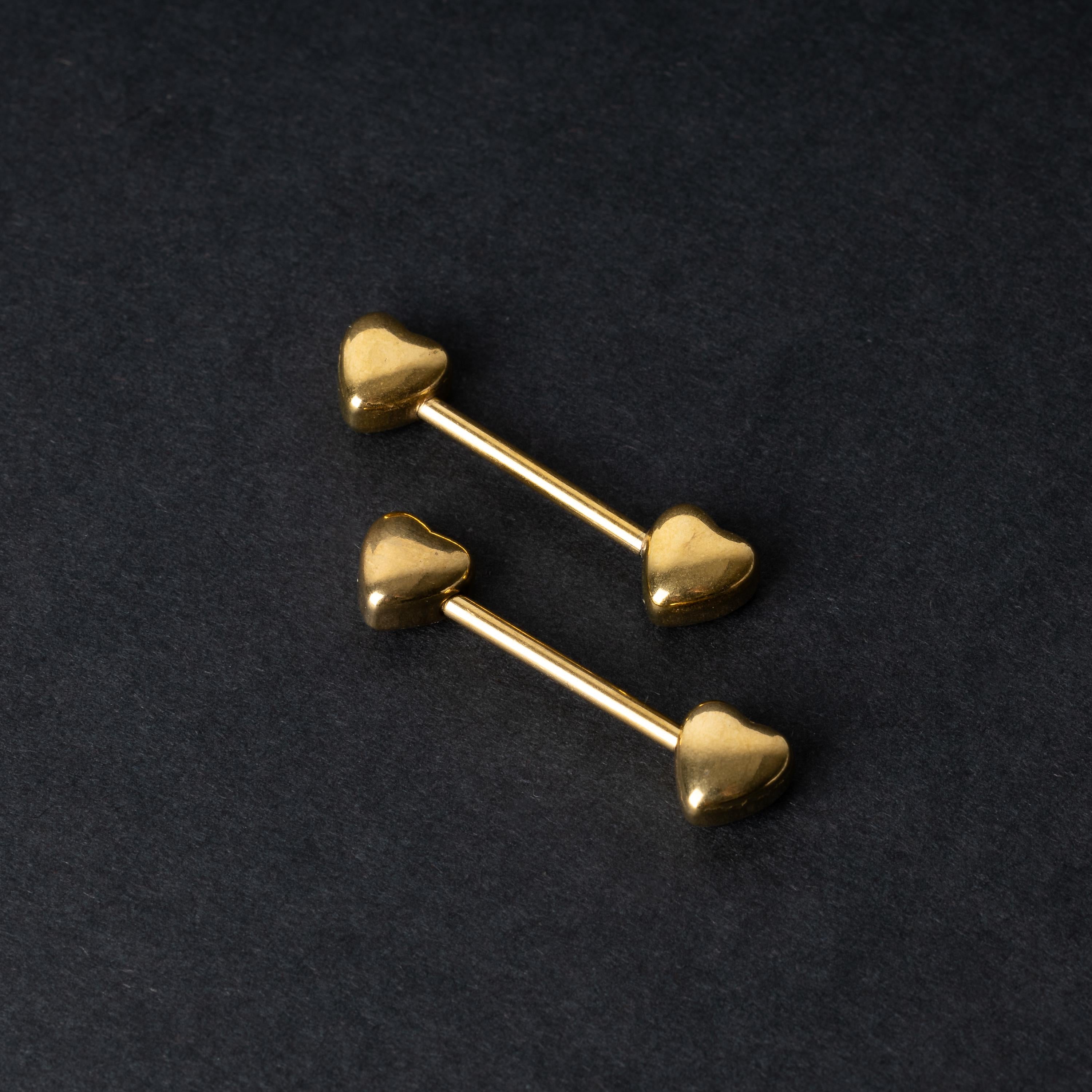 Heart-shaped gold barbells on a dark background.