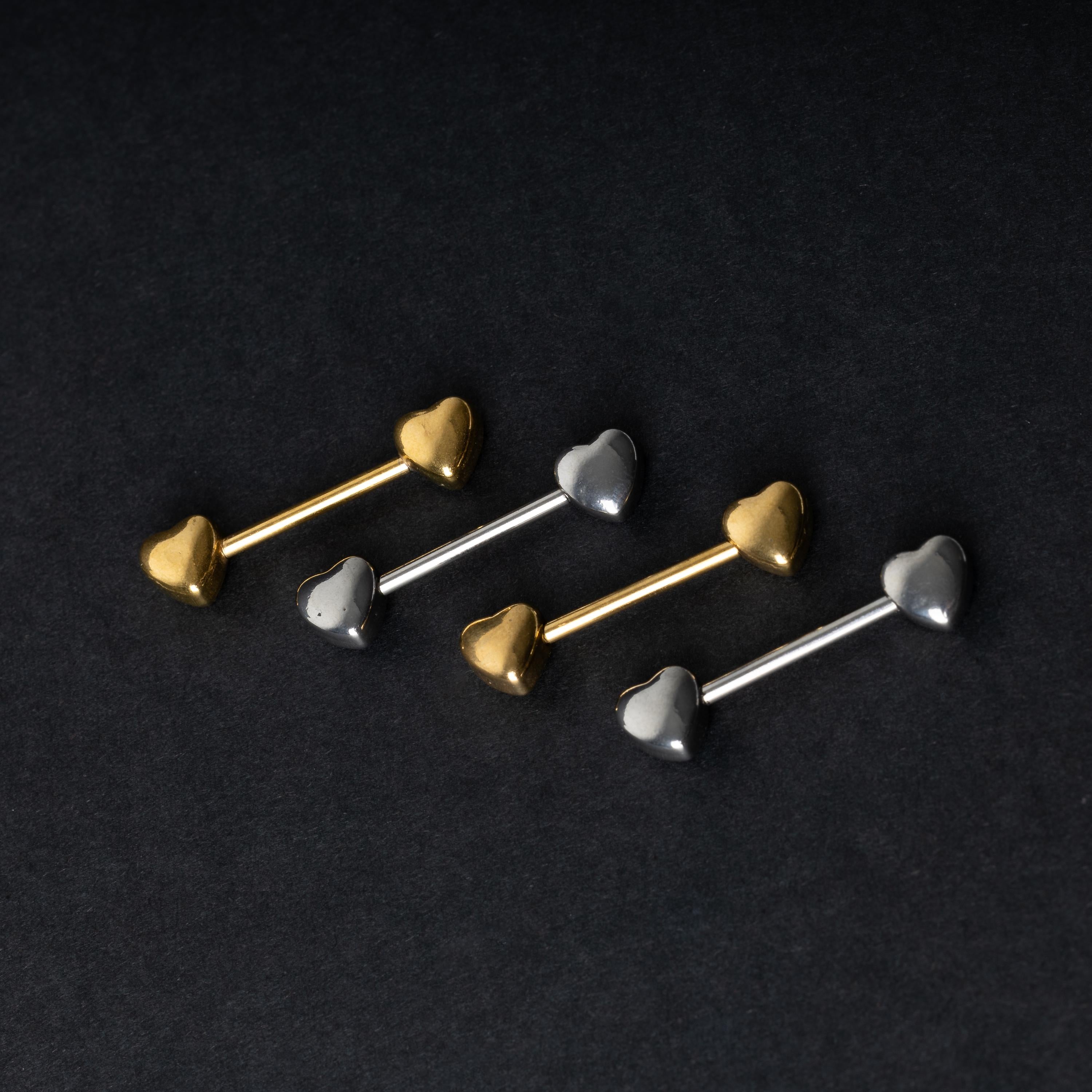 Heart-shaped silver and gold barbells on a dark background.