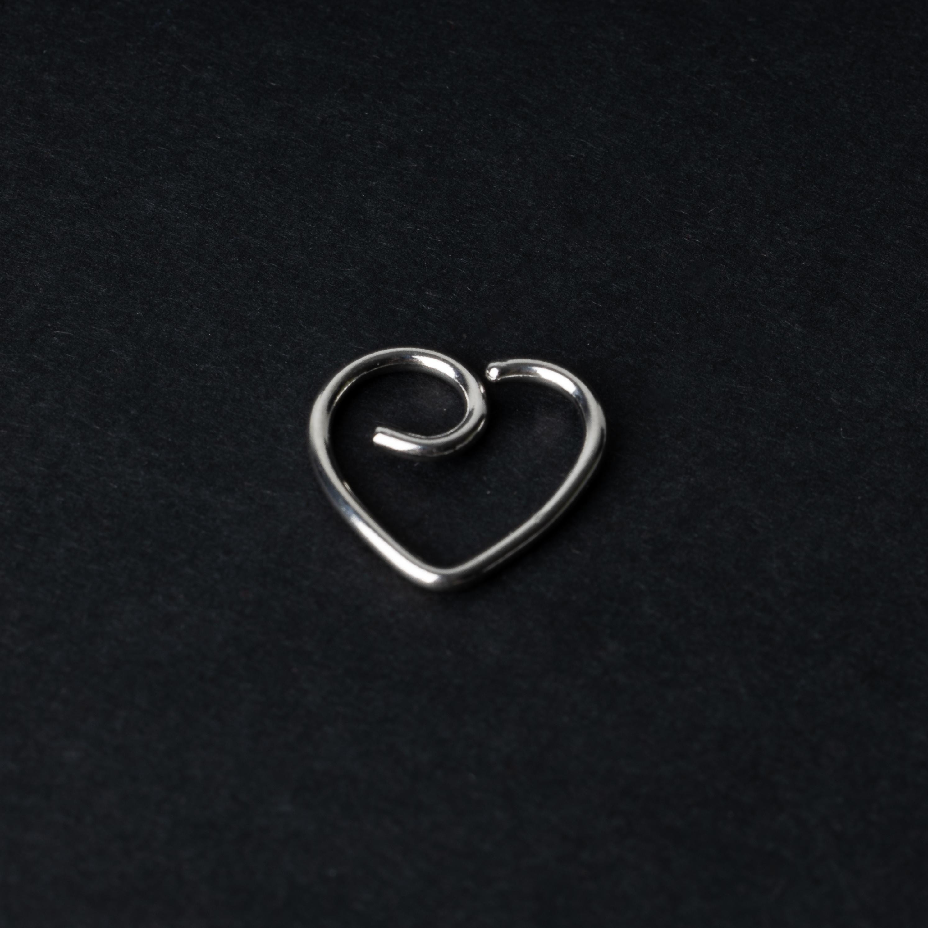 Silver heart shaped daith on a dark background