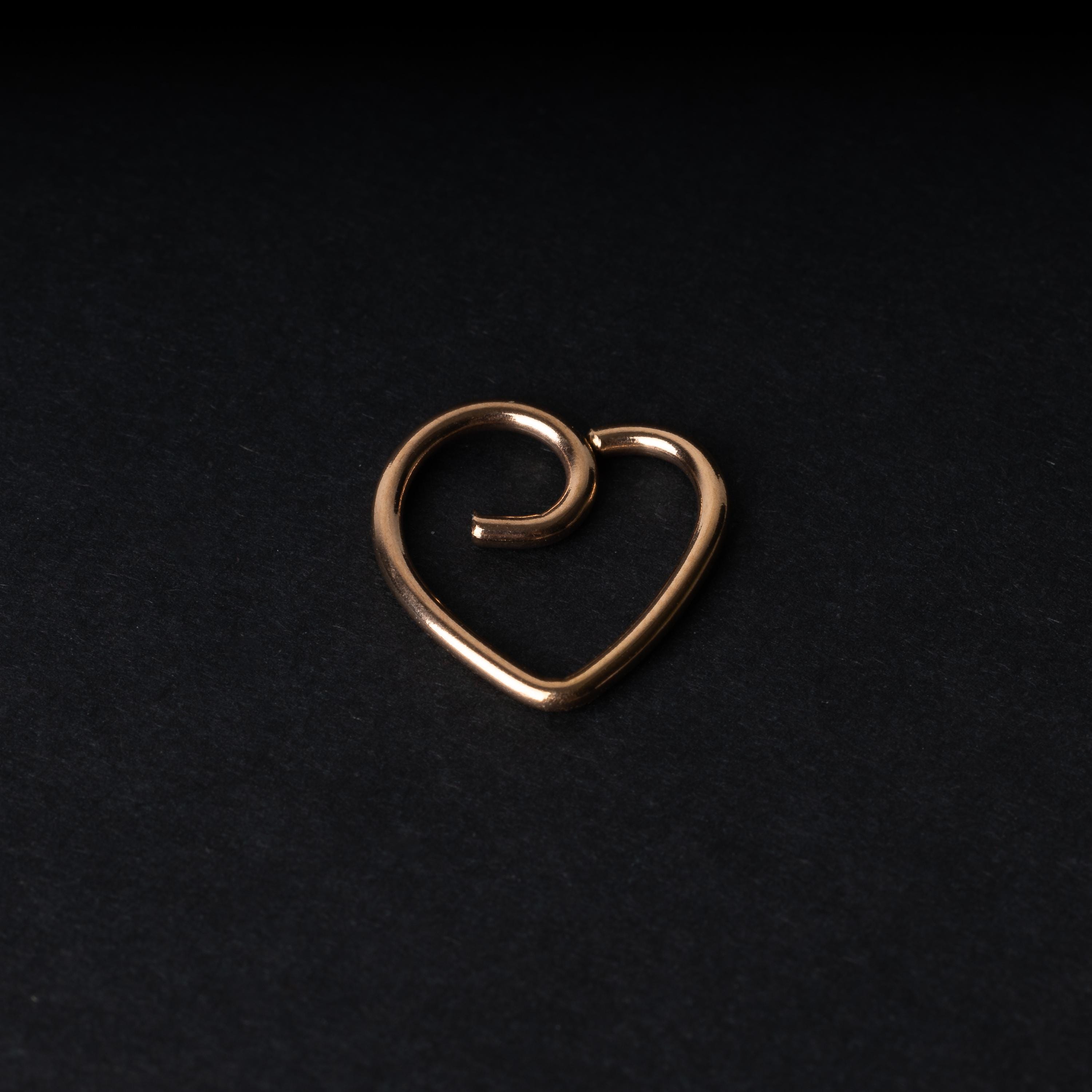Rose gold heart shaped daith on a dark background