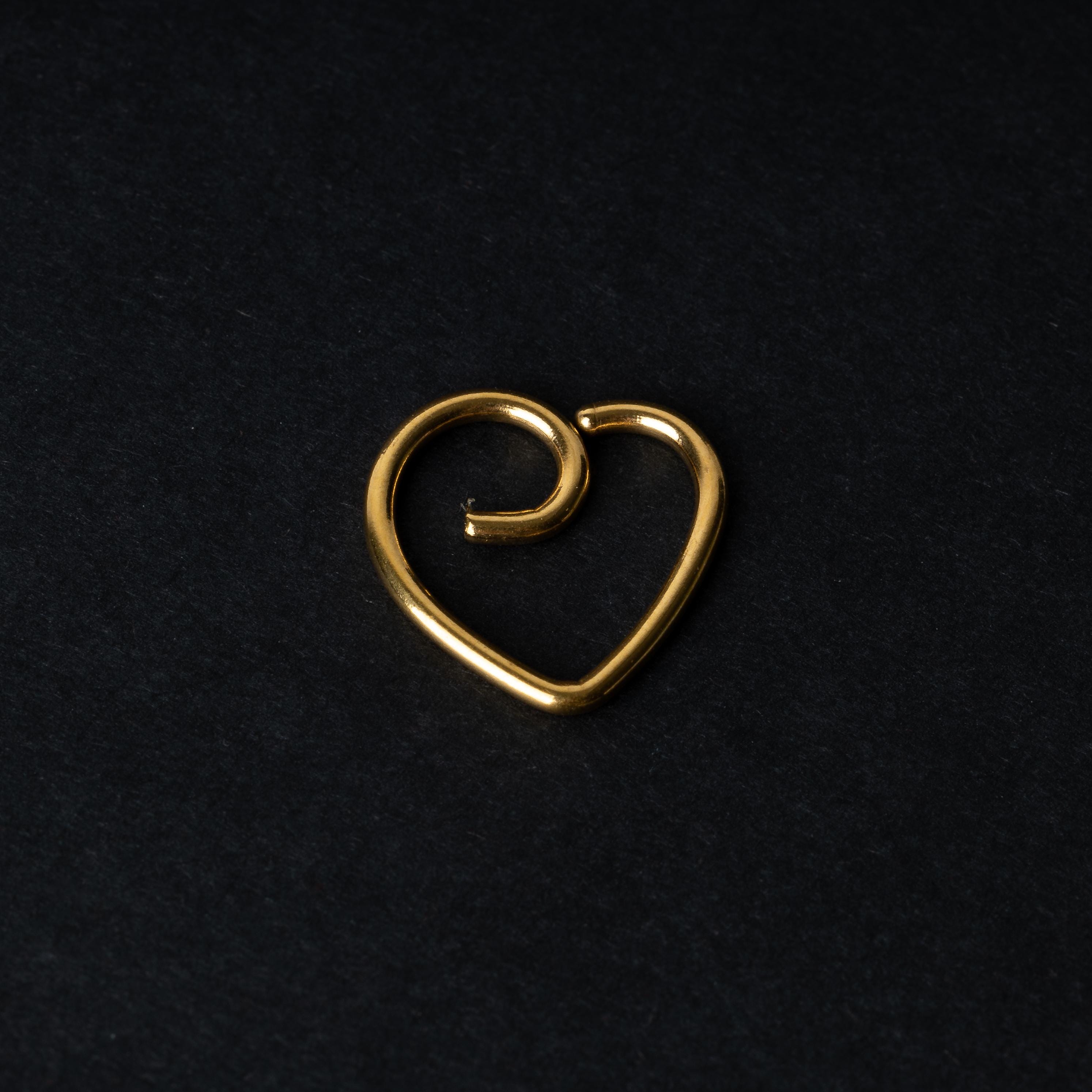 Gold heart shaped daith on a dark background