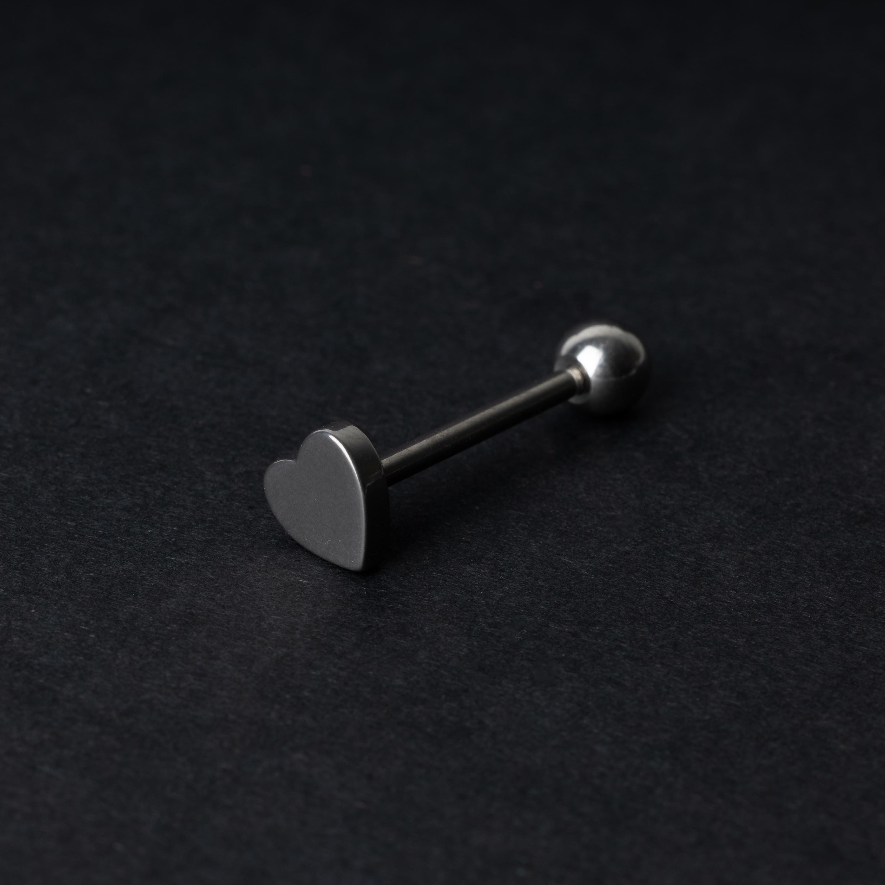 Heart shaped tongue bar in silver, displayed on a dark background.