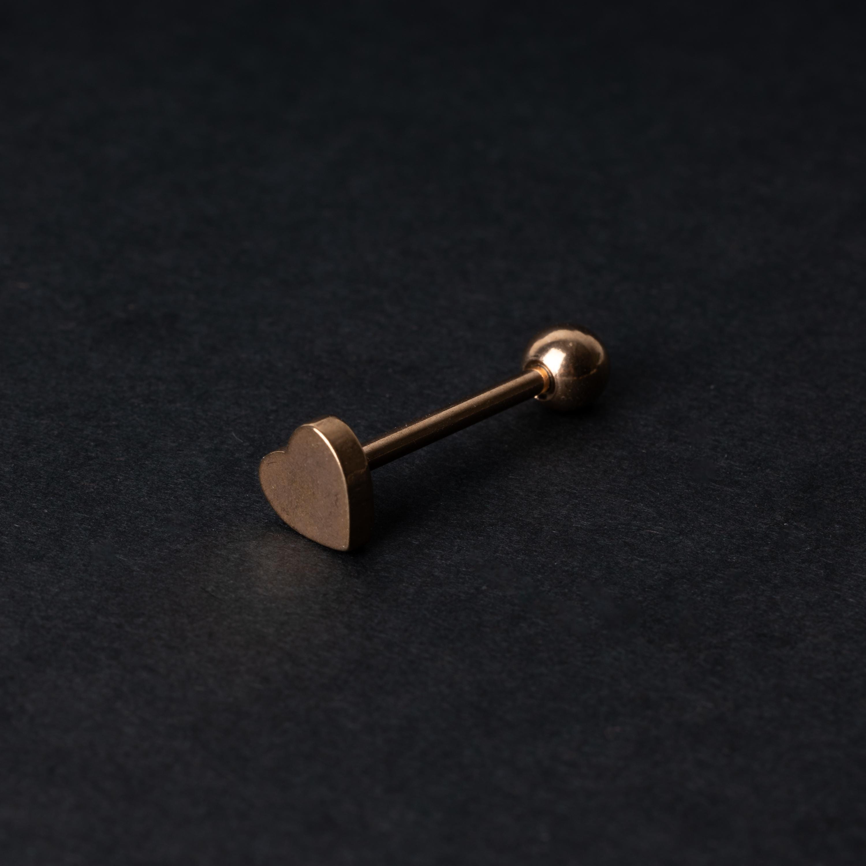 Heart shaped tongue bar in rose gold, displayed on a dark background.