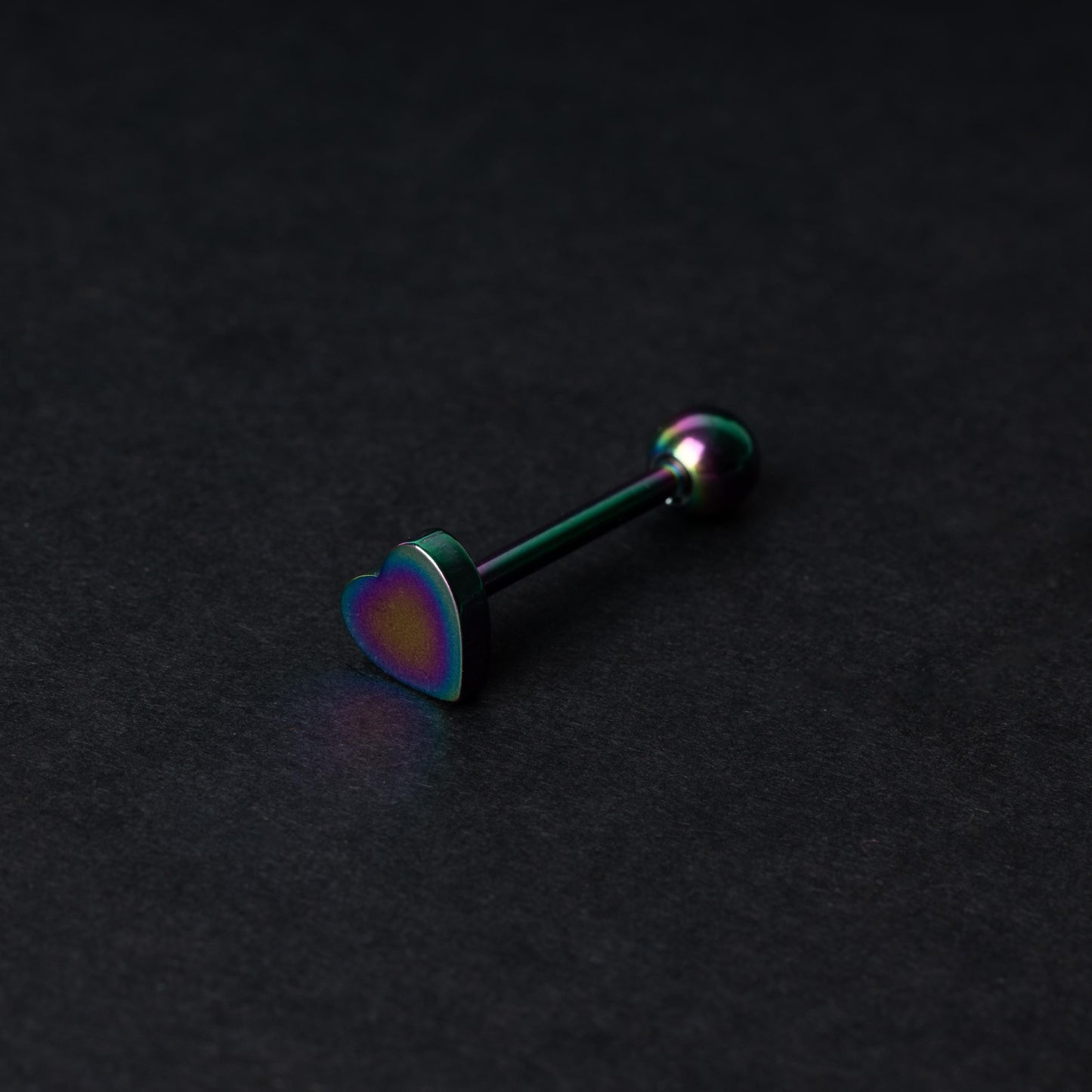 Heart shaped tongue bar in rainbow, displayed on a dark background.