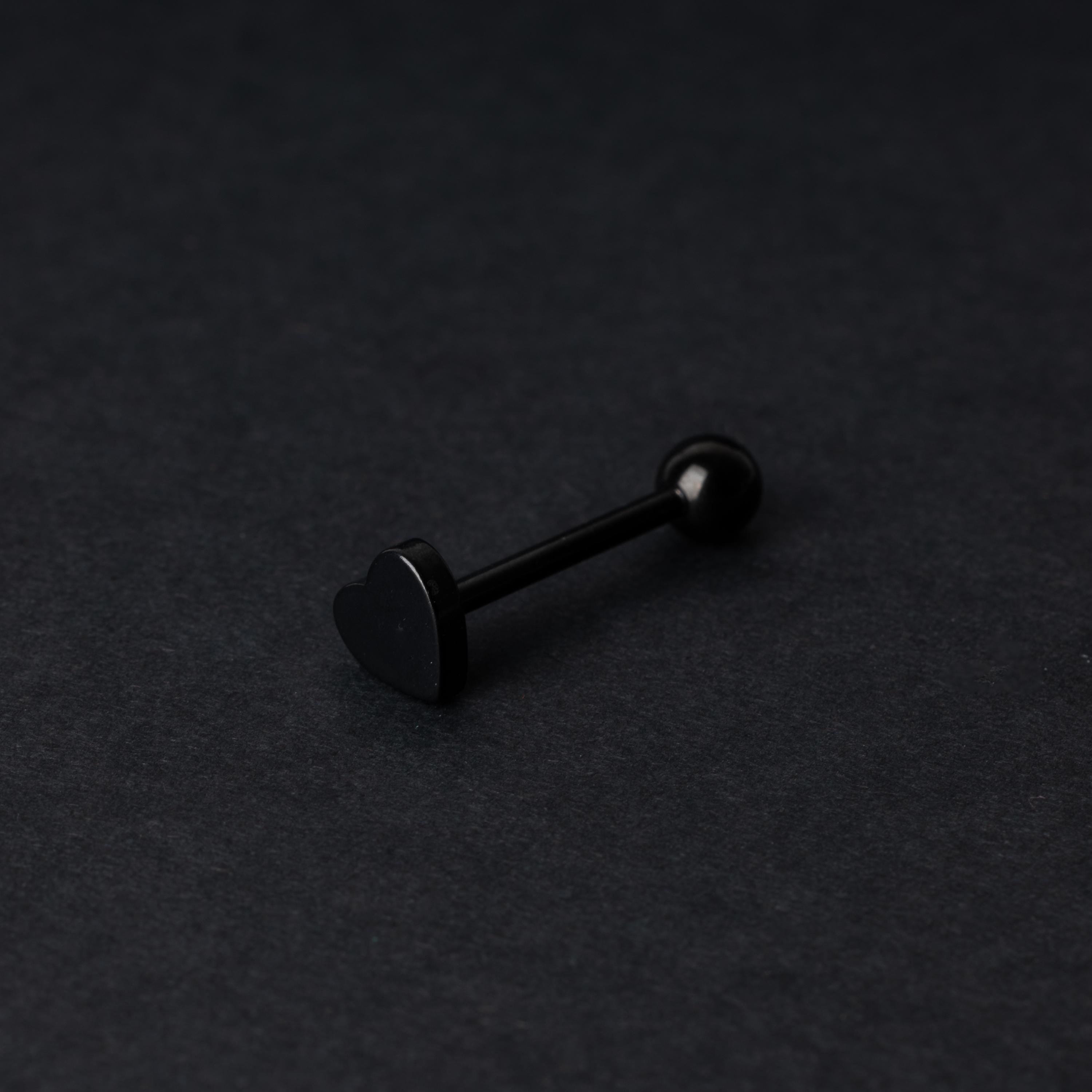 Heart shaped tongue bar in black, displayed on a dark background.