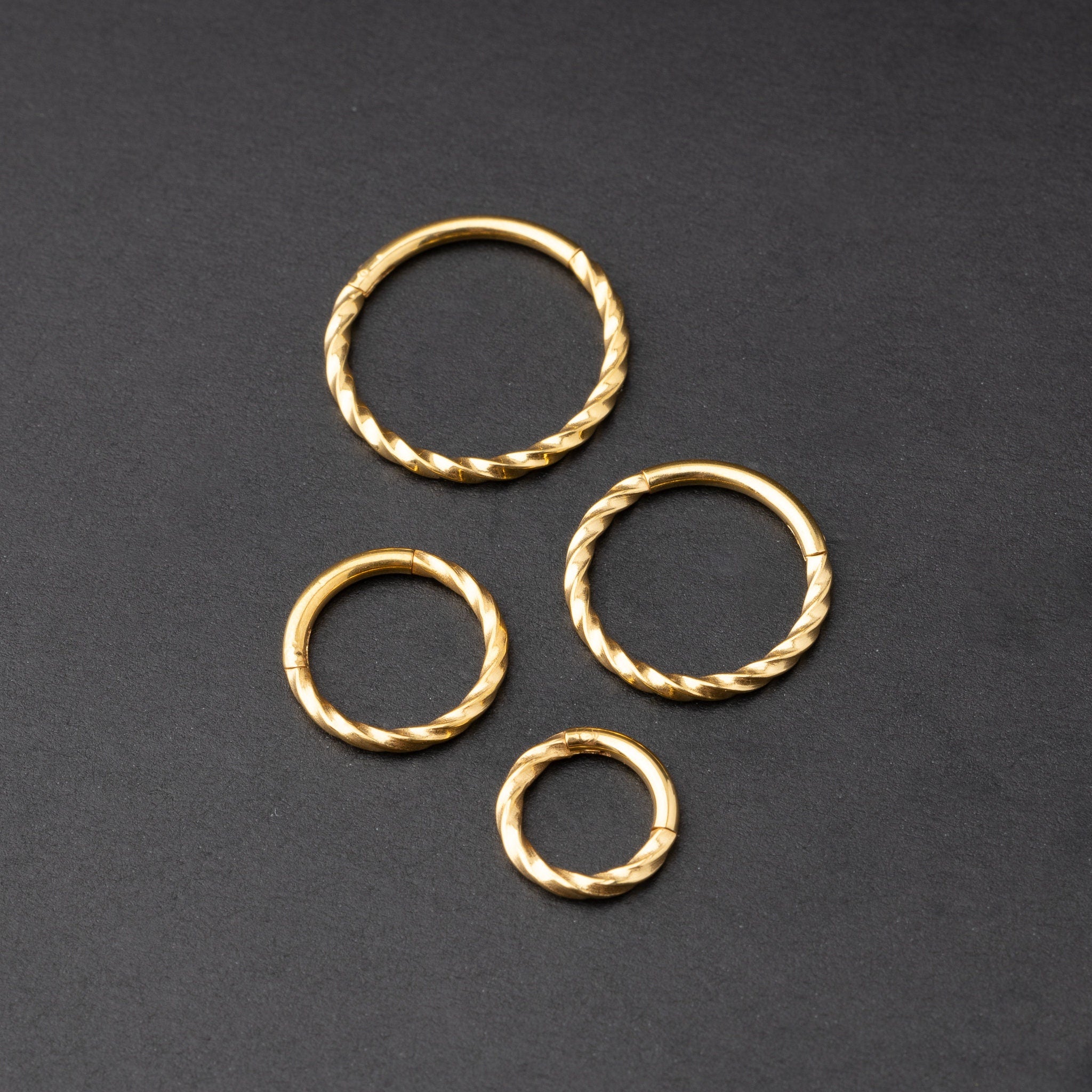 Gold seamless rings with a twisted rope texture, shown in four sizes on a dark background.