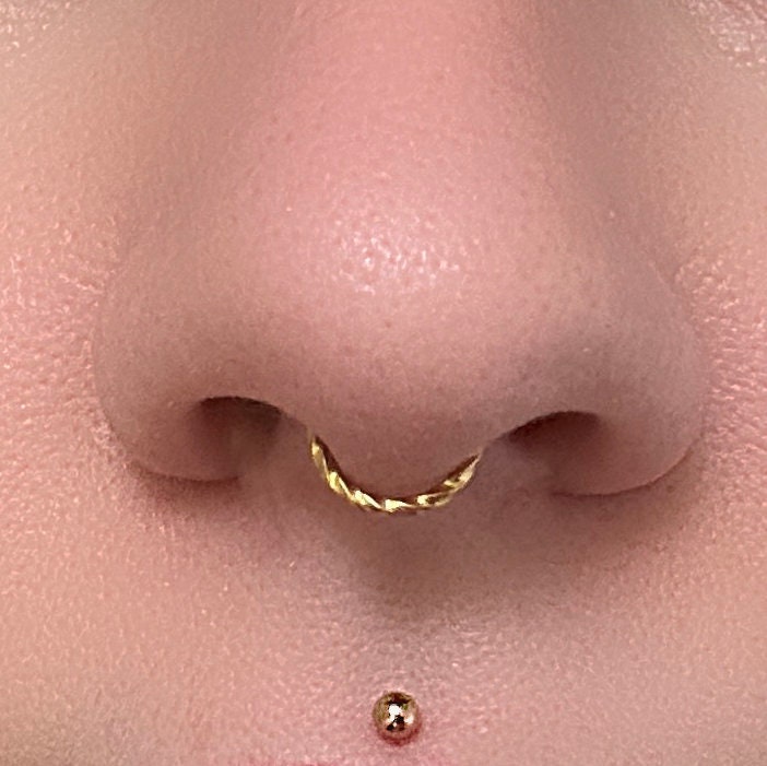 Gold seamless ring displayed in the septum of a model.