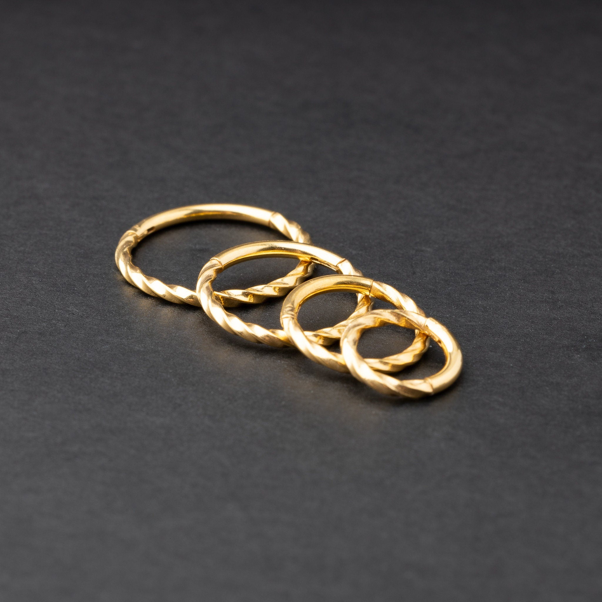 Gold seamless rings with a twisted rope texture, shown in four sizes on a dark background.